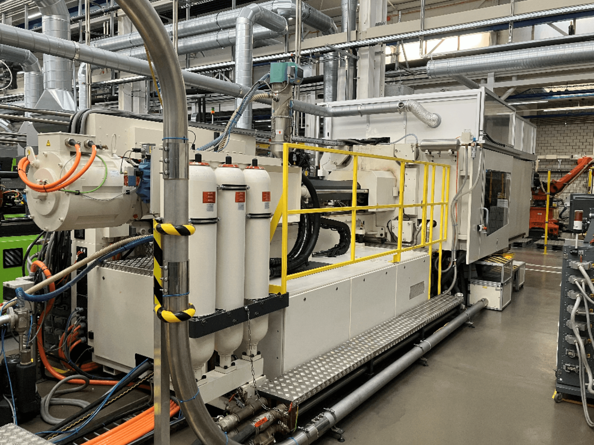 Industriemaschine mit weißem und grauem Gehäuse, mehreren Schläuchen und Filterbehältern; Seitenansicht, die die Betriebseinrichtung zeigt.