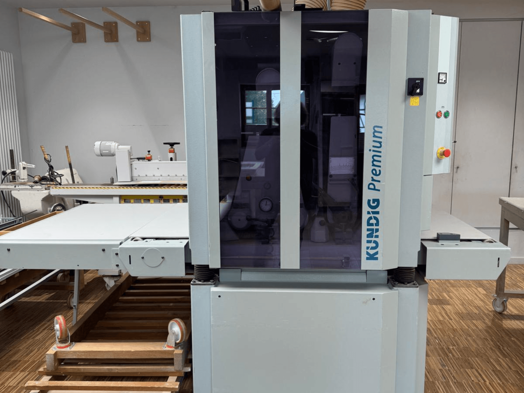 Kundig Premium 2-1100-RP Bandschleifmaschine in der Frontansicht mit Bedienfeld und großer Glasabdeckung für bessere Sicht.