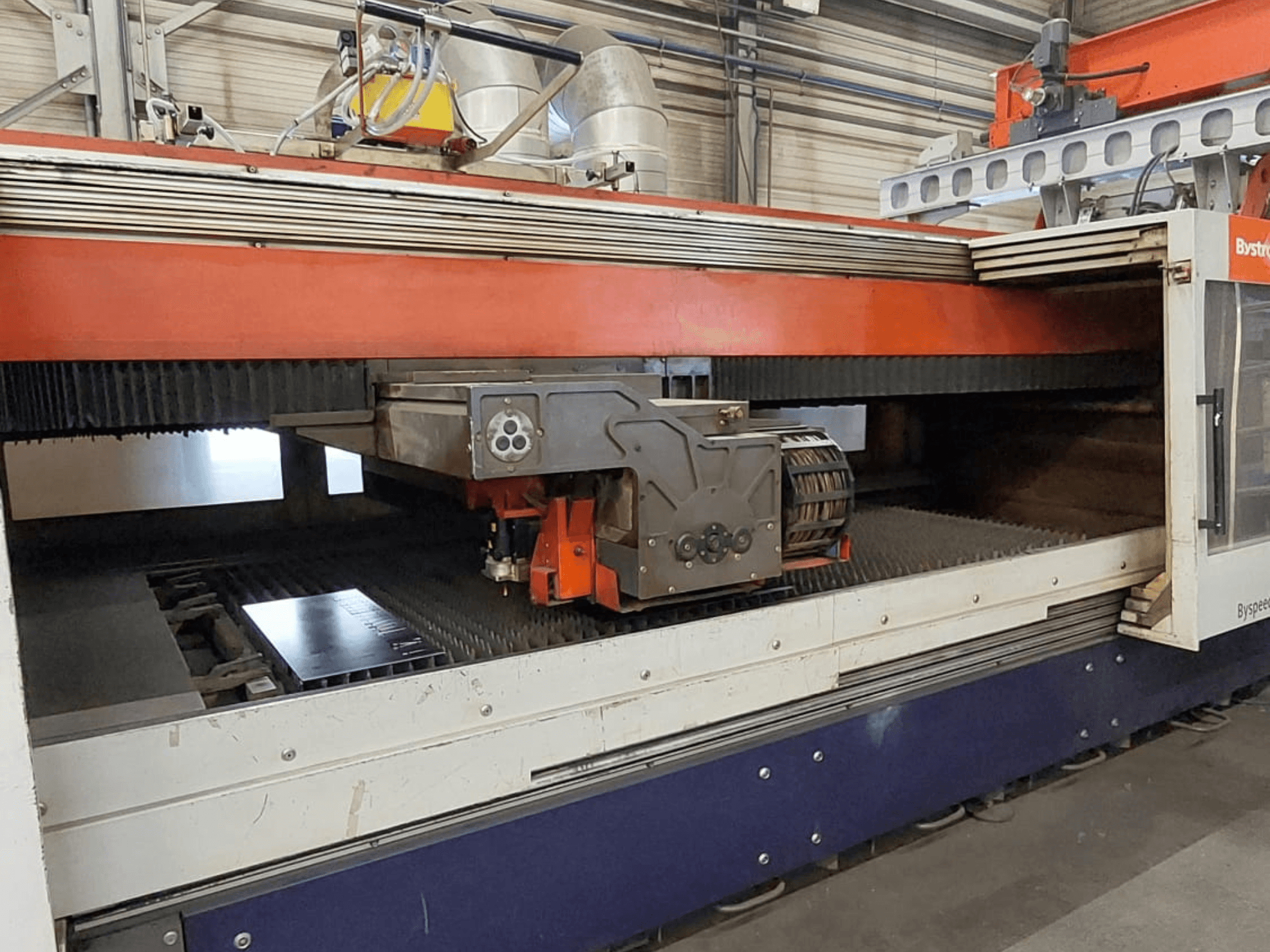 Bystronic BySpeed 3015 CO₂-Laserschneidanlage, Vorderansicht mit Schneidkopf und Blech auf dem Schneidtisch.