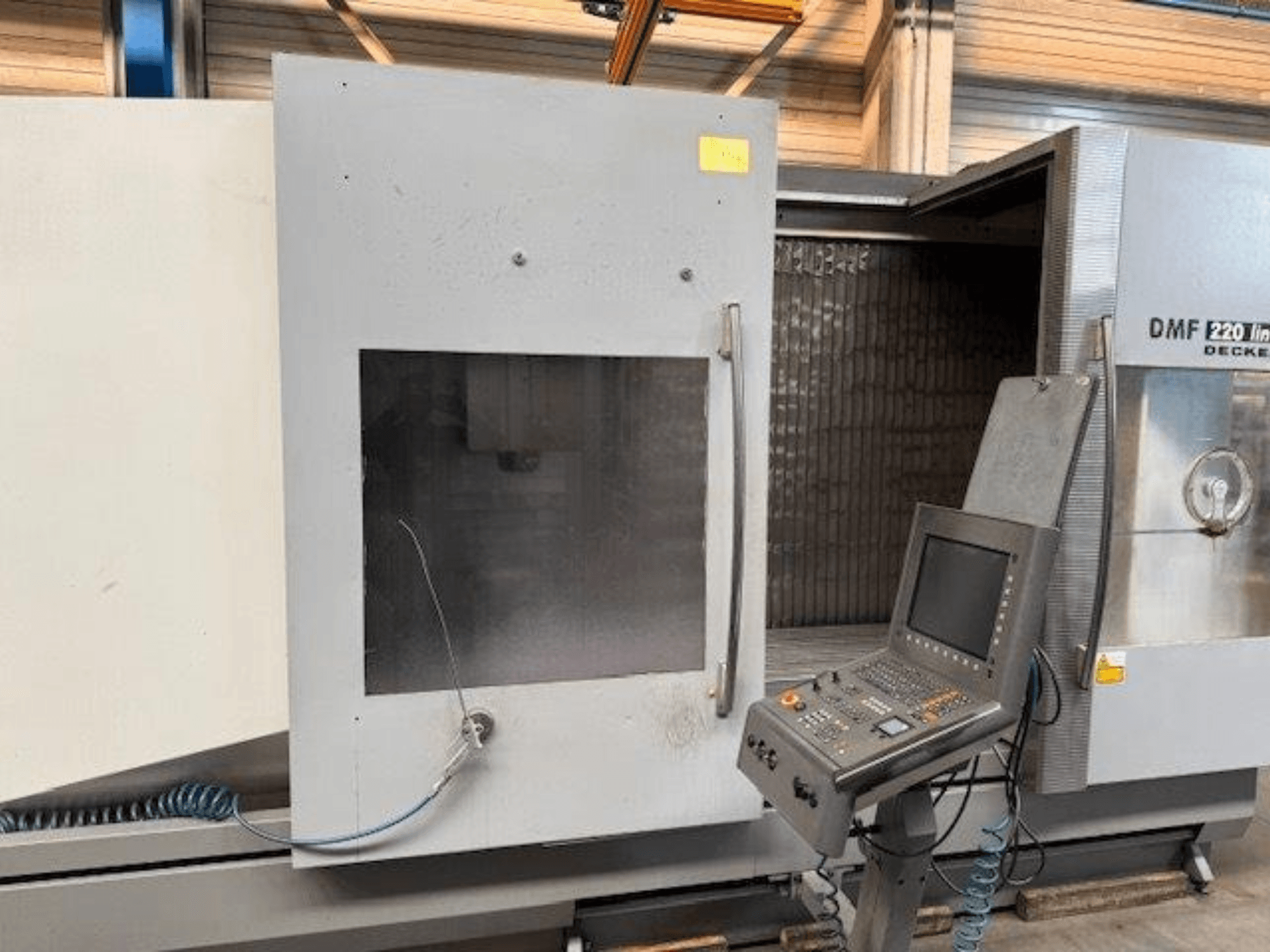 Frontansicht des DECKEL MAHO DMF 220 Linear-Vertikal-Bearbeitungszentrums mit Blick auf das Bedienfeld und die geöffnete Maschinentür.