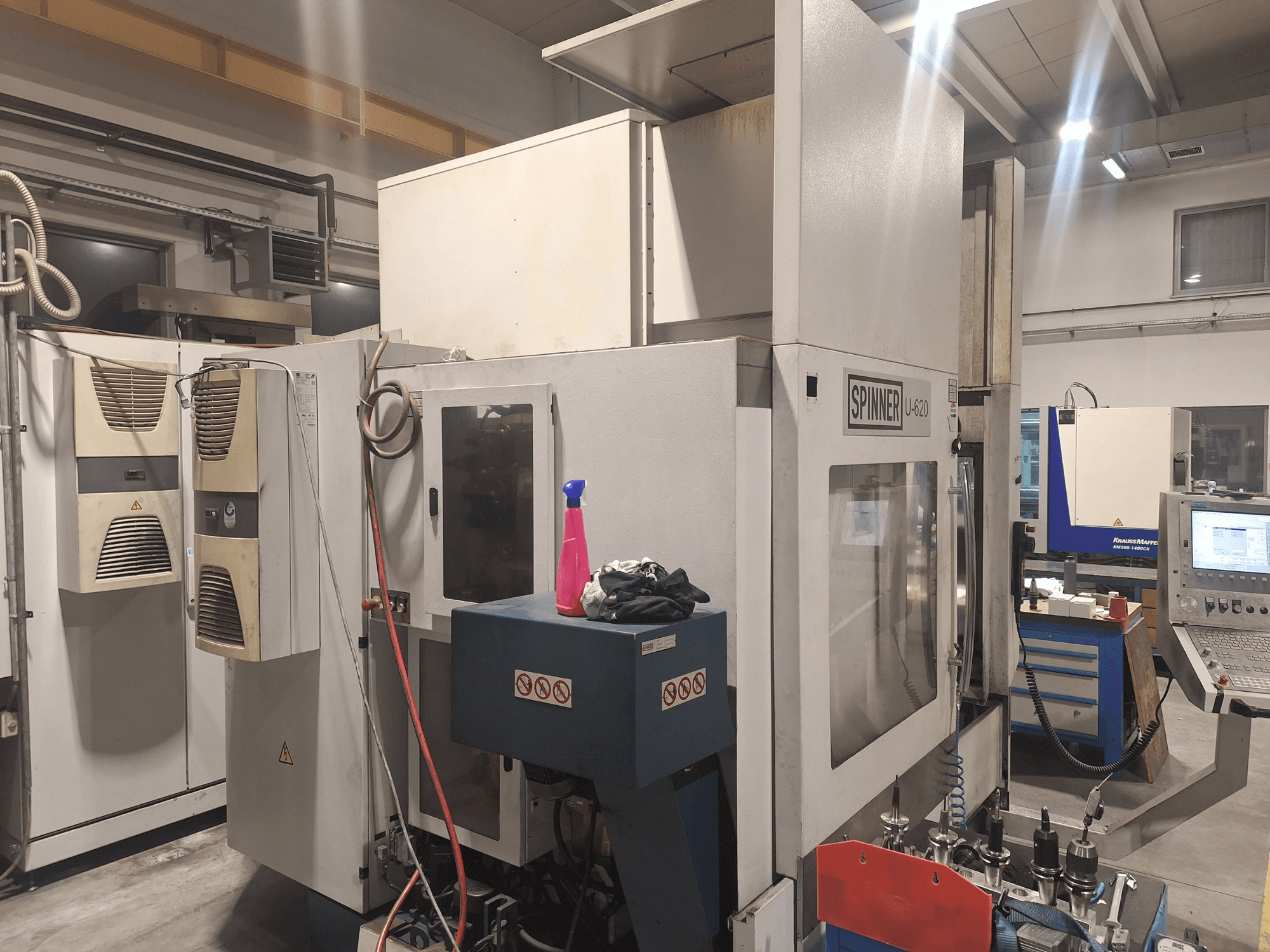 CNC-Maschine Spinner U-620 in der Frontalansicht in einer Werkstatt, mit Bedienfeld und verschiedenen Werkzeugen auf einer Werkbank in der Nähe.