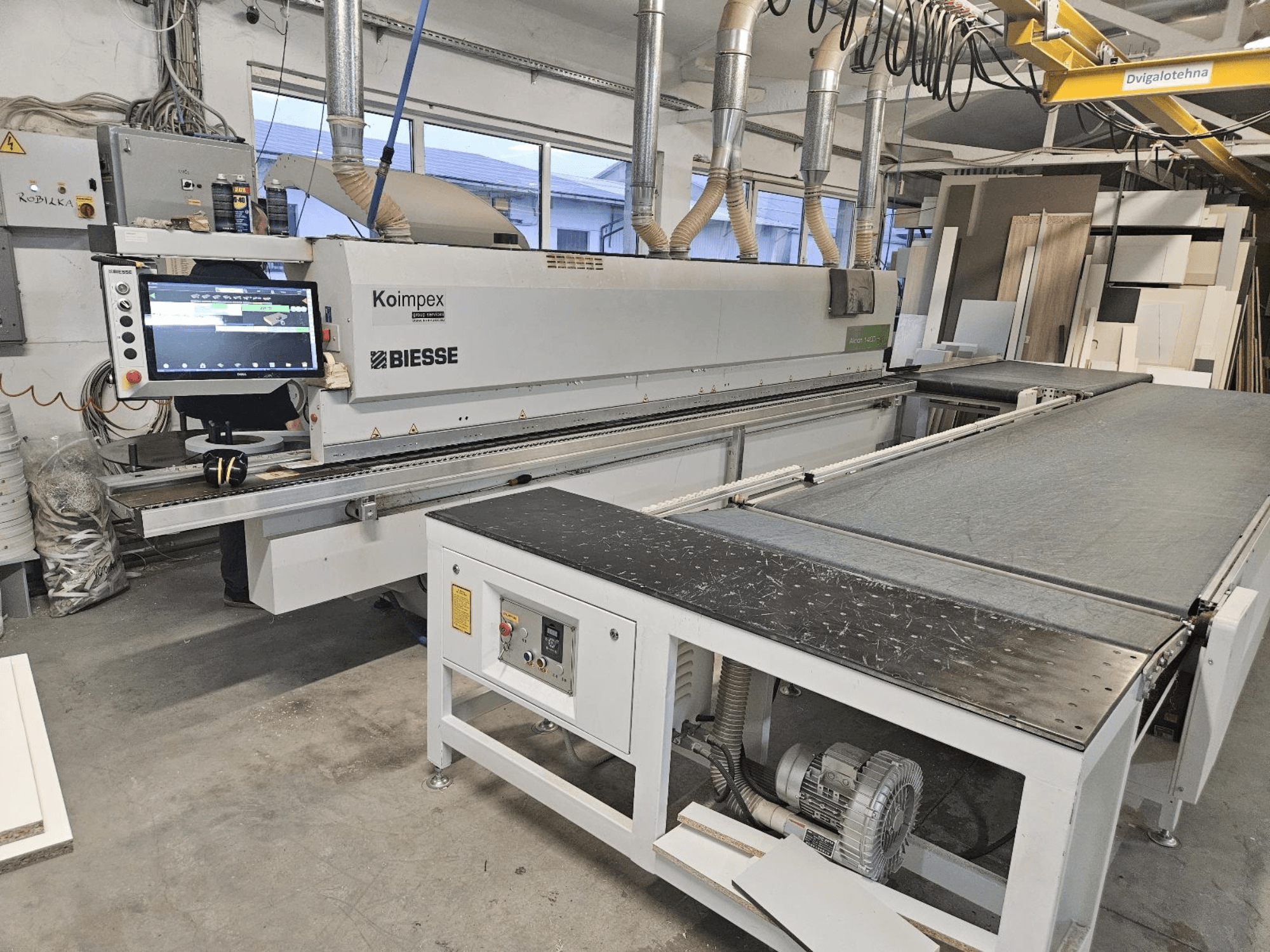 BIESSE Akron 1440 Eine Kantenanleimmaschine in einer Werkstatt, Seitenansicht mit Bedienfeld und Transportband.