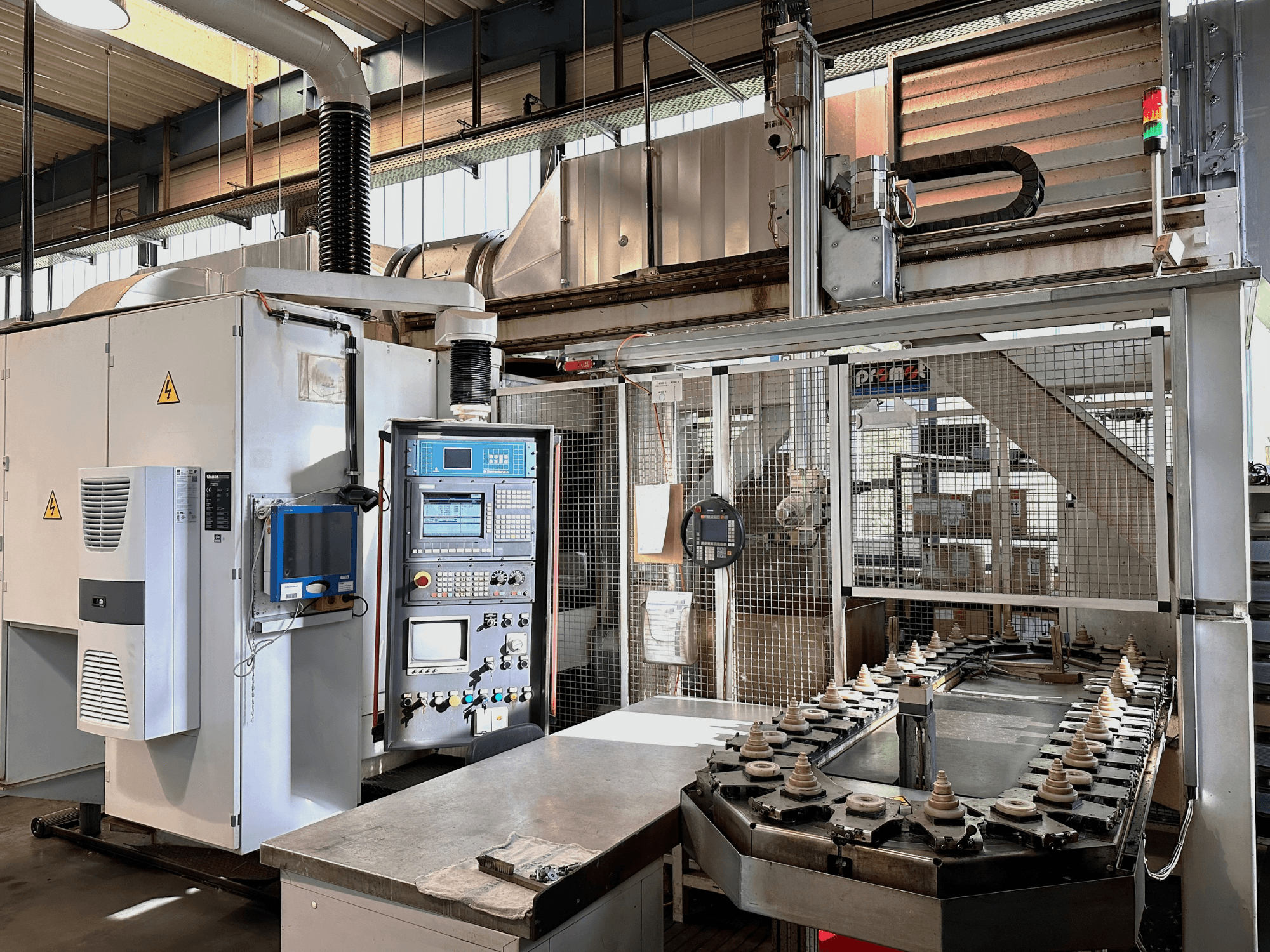 Industriemaschine mit Schalttafel, Kühlaggregat und Förderband. Frontansicht mit hellen Lichtern und Sicherheitsschildern.