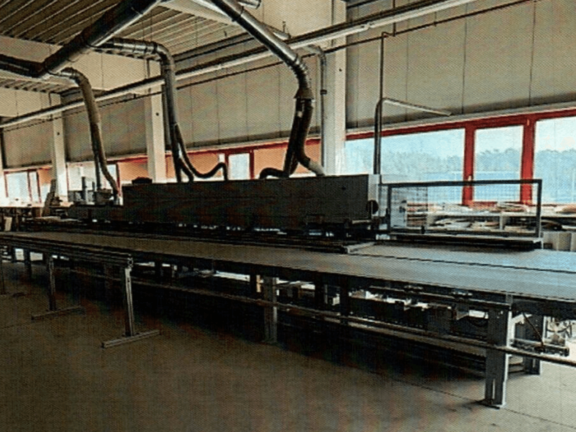 HOMAG KAL 370 Kantenanleimmaschine in einer Werkstatt, Seitenansicht mit dem langen, flachen Arbeitstisch und den darüber liegenden Lüftungskanälen.