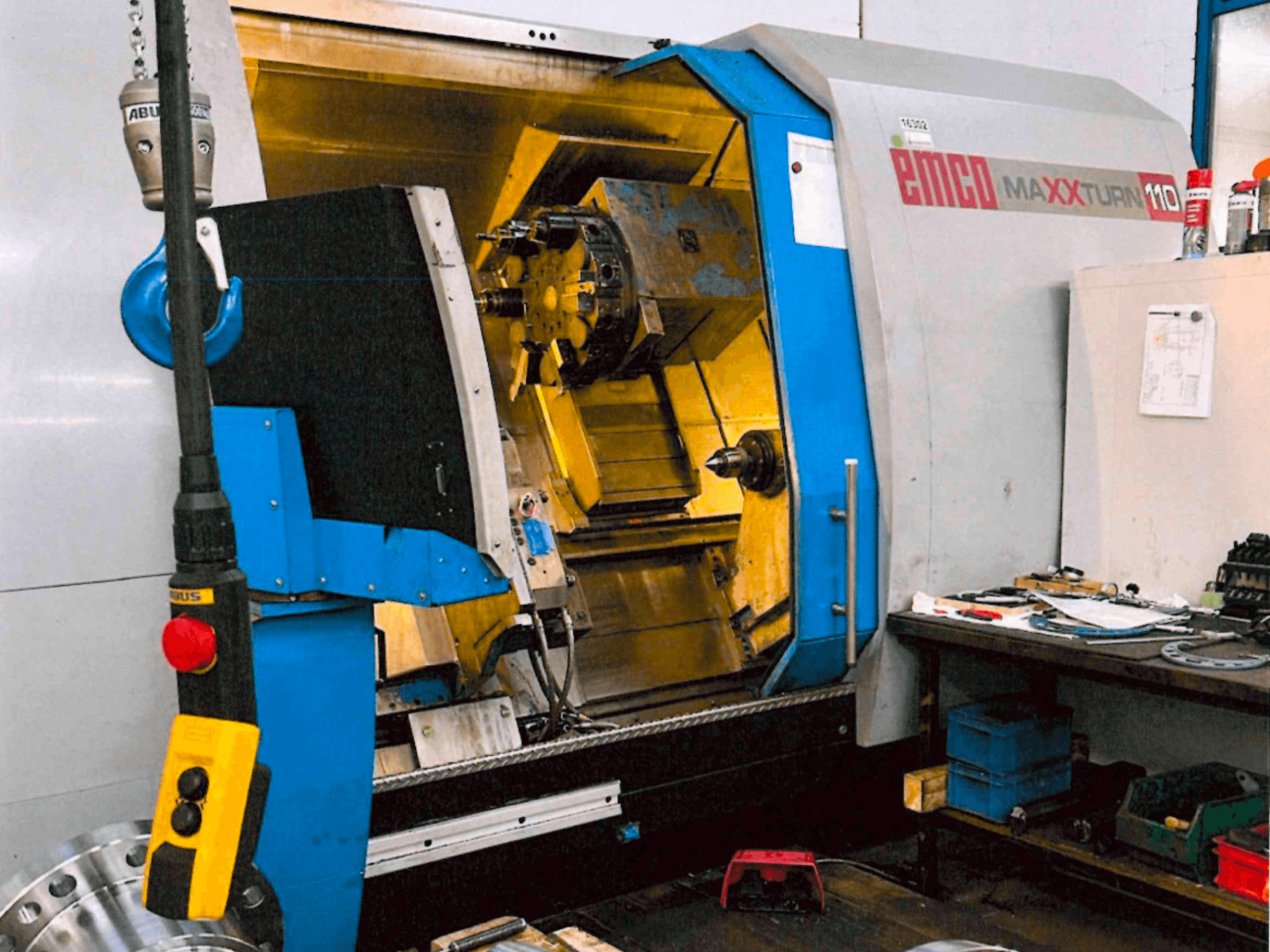 Horizontale EMCO MAXTURN 110-Drehmaschine, Vorderansicht, mit Einblicken in die inneren Bauteile und das Bedienfeld, in einer Werkstattumgebung.