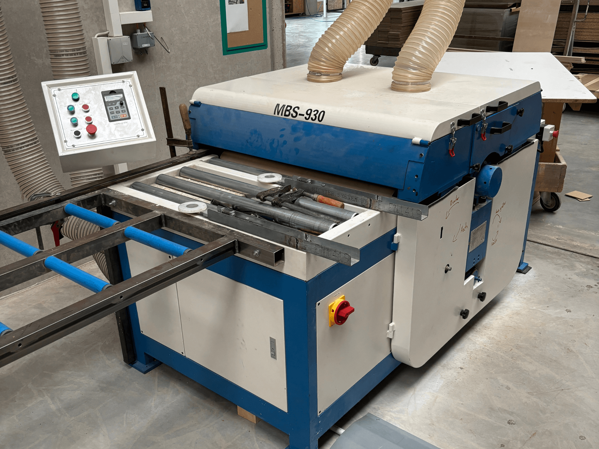 Holzbearbeitungsmaschine MBS-930 mit Bedienfeld und Walzen, von der Seite gesehen, mit Absaugschläuchen.