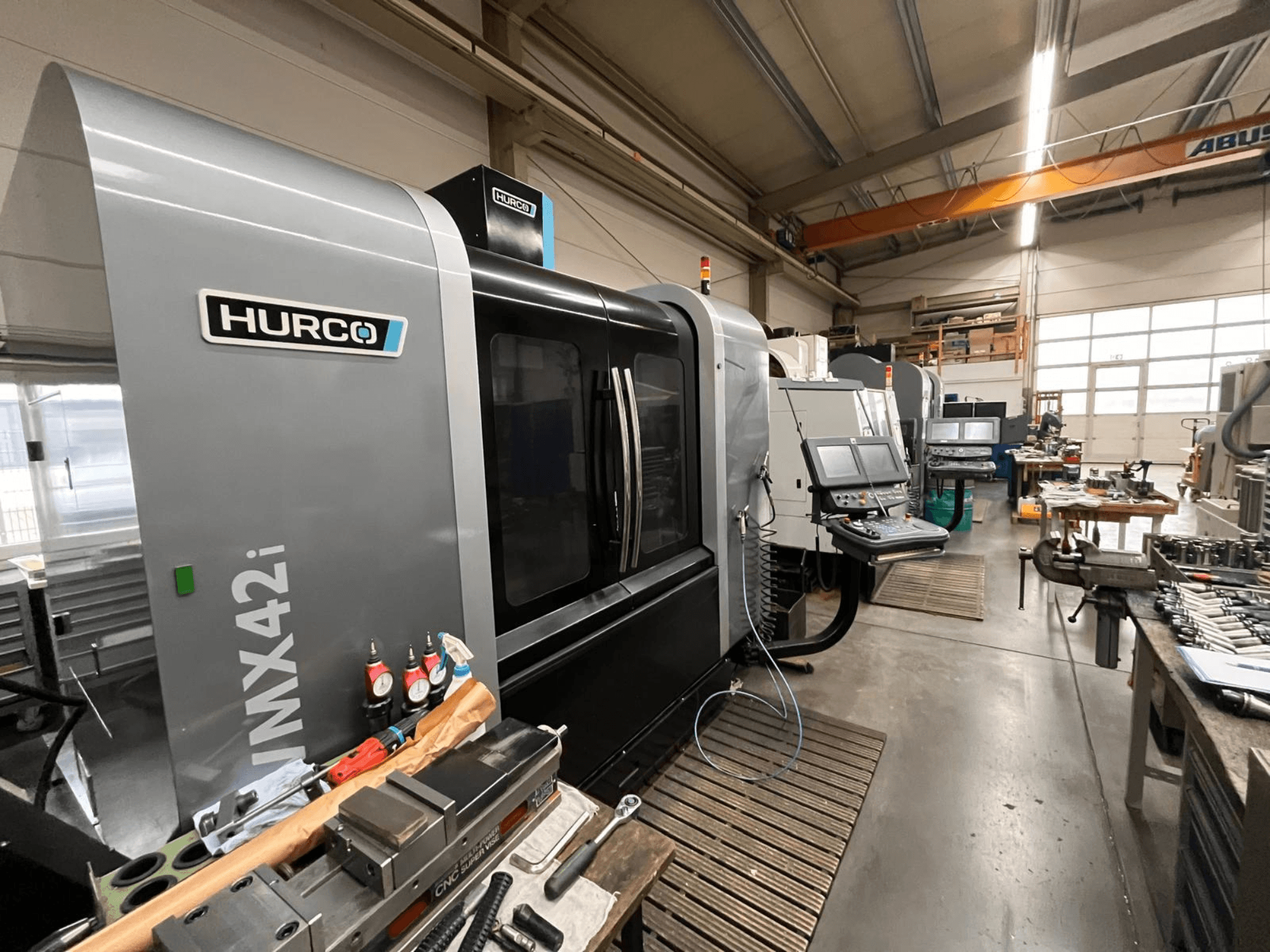 Hurco VMX42i CNC-Maschine in einer Werkstatt, Vorderansicht. Mit Bedienfeld, grauem Gehäuse und industrieller Umgebung.