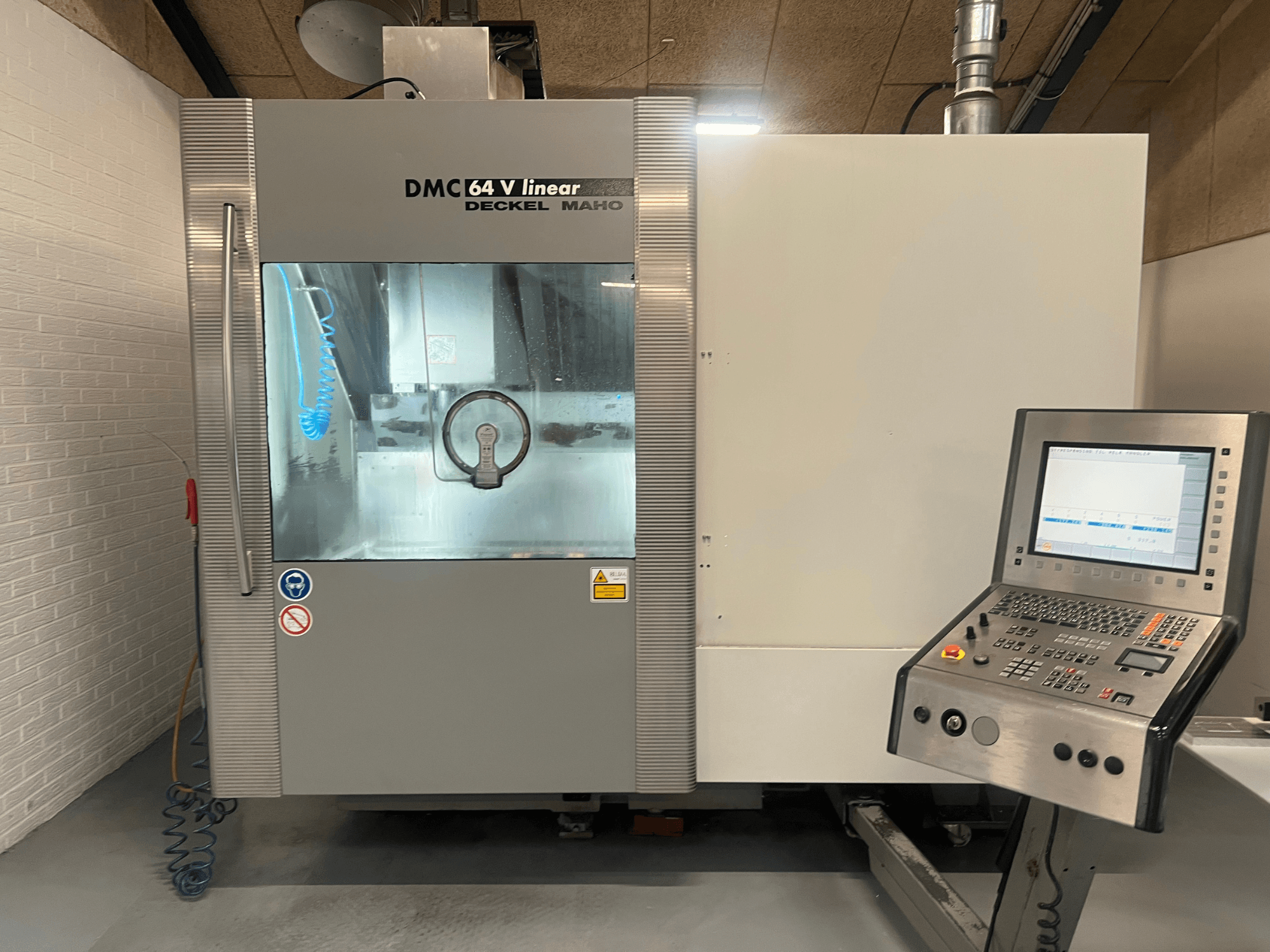 DMC 64 V Linear von Deckel Maho, Frontansicht des CNC-Bearbeitungszentrums mit Bedienfeld und Kühlmitteldüse.