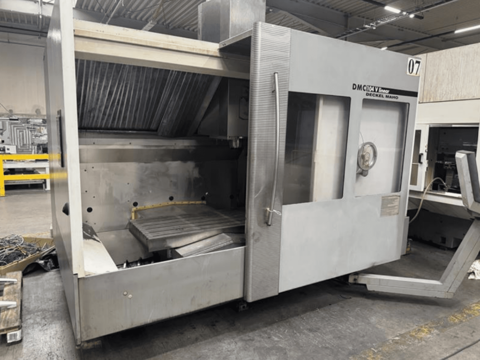 DMC 104 V Linearmaschine von Deckel Maho, Vorderansicht, mit einem leeren Arbeitsraum und einem großen Arbeitstisch.