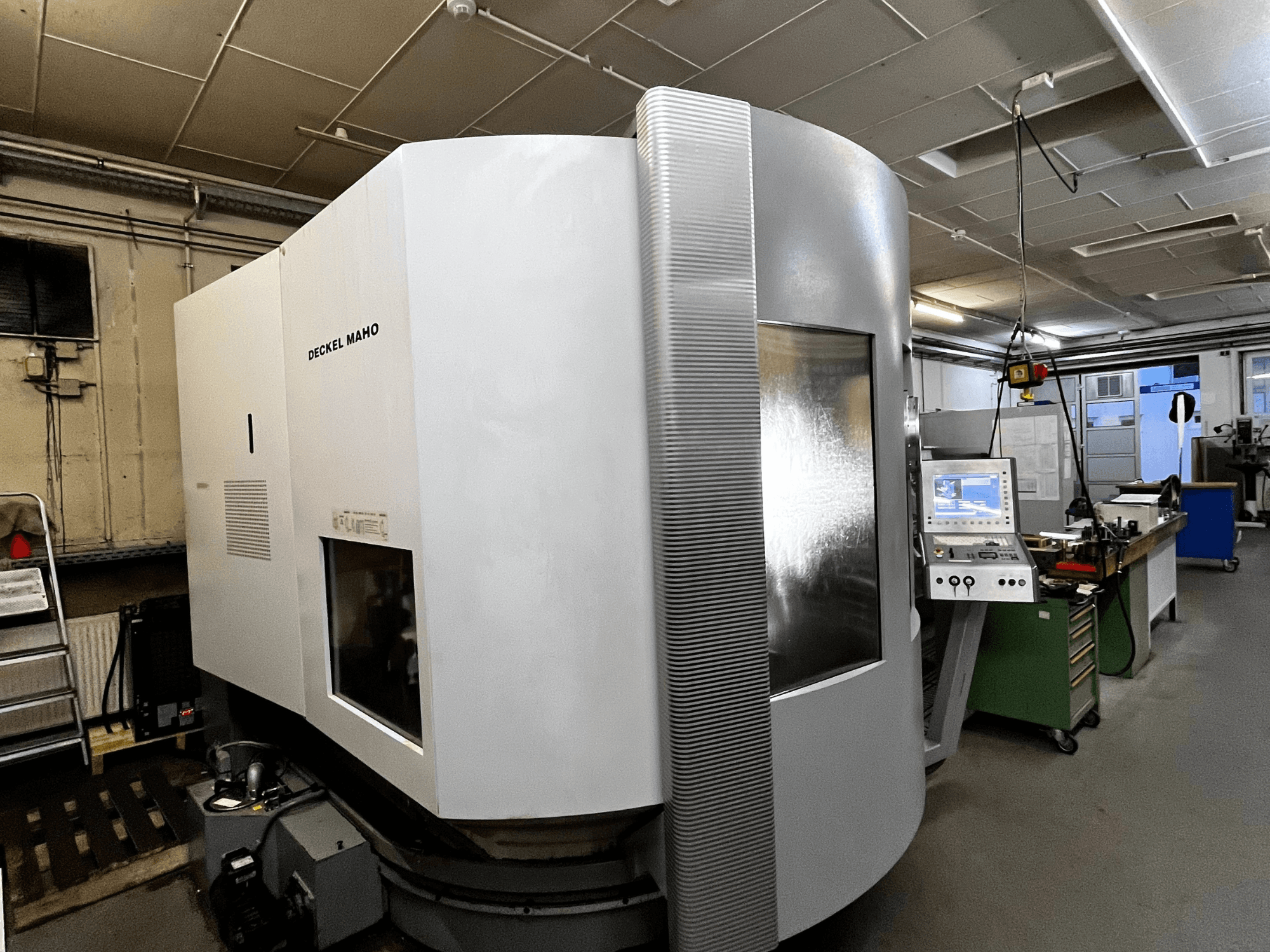 Deckel Maho CNC-Maschine, Vorderansicht, weißes Äußeres, Bedienfeld sichtbar, Werkstattumgebung.