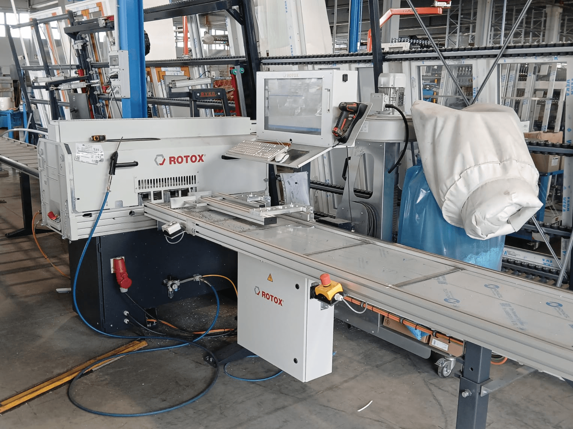 Vorderansicht einer Rotox GLA401-Kunststoffverarbeitungsmaschine mit Bedienfeld, Förderband und sichtbaren Schläuchen in einer Industrieumgebung.