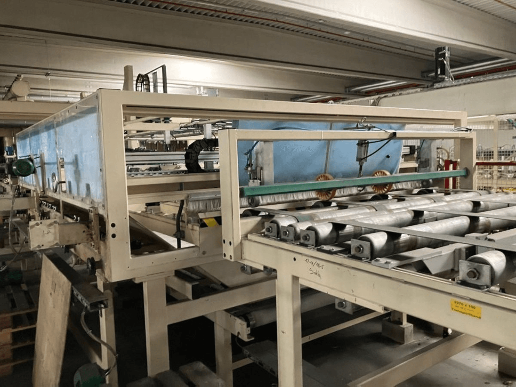 WEMHÖNER KT-F-1E Kaschierpresse, Seitenansicht, mit Walzen und Steuerung für die Materialverarbeitung in der Fabrik.