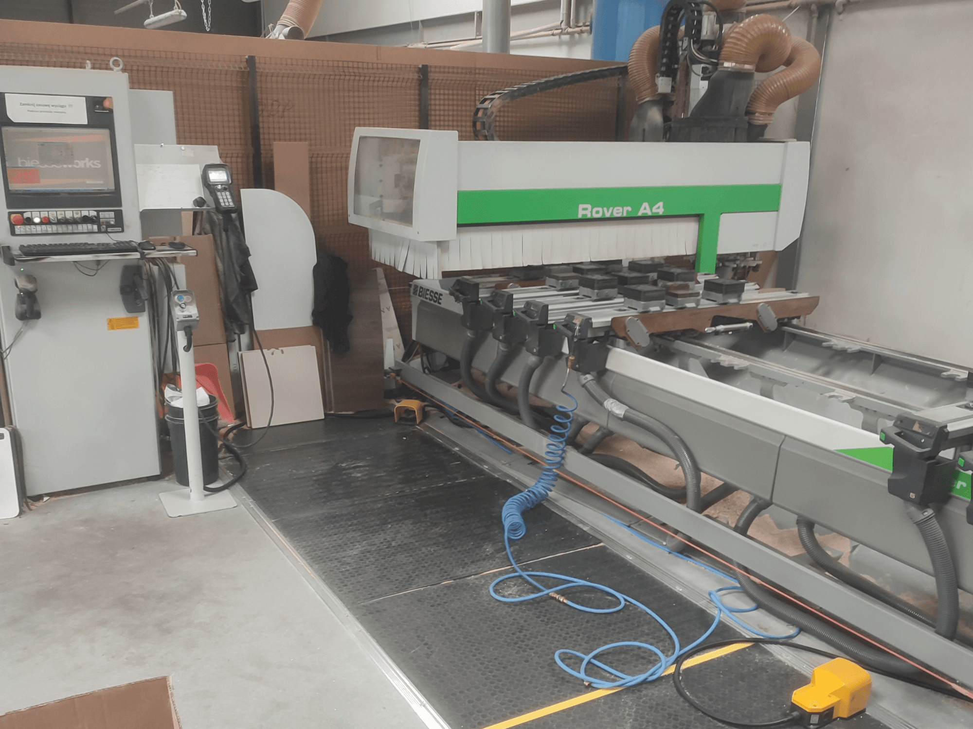 BIESSE Rover A4 CNC-Holzbearbeitungszentrum in Seitenansicht, mit Blick auf das Bedienfeld, die Vakuumspannvorrichtungen und die Staubabsauganlage.