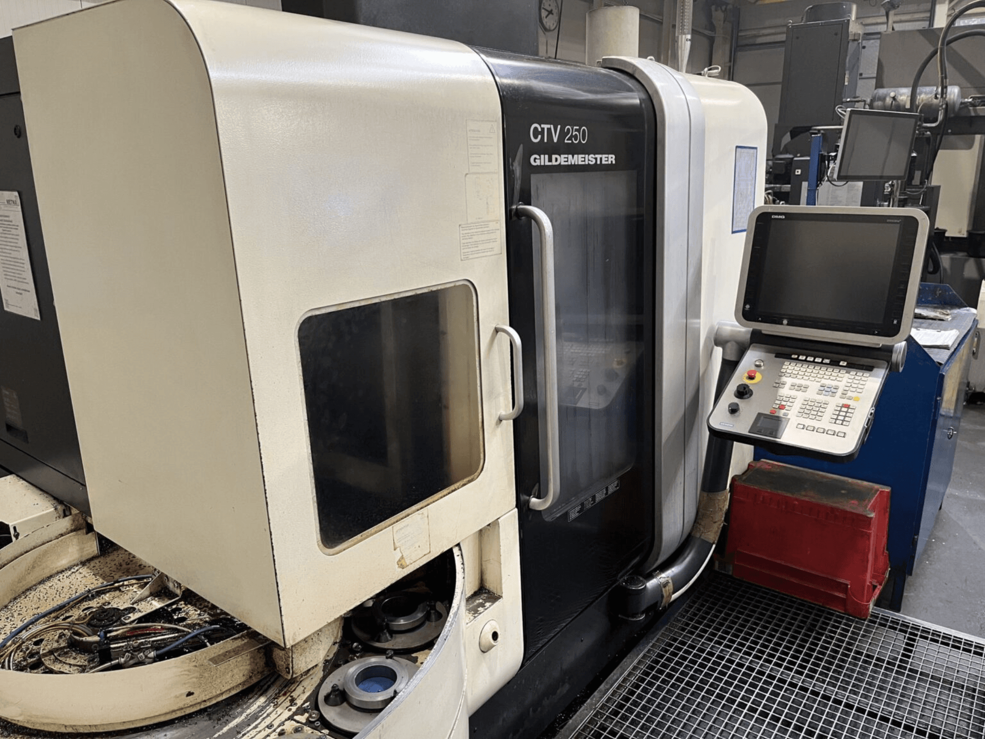 Vertikaldrehmaschine DMG CTV-250 in der Frontalansicht mit Bedienfeld und Arbeitsbereich mit Werkzeugen.