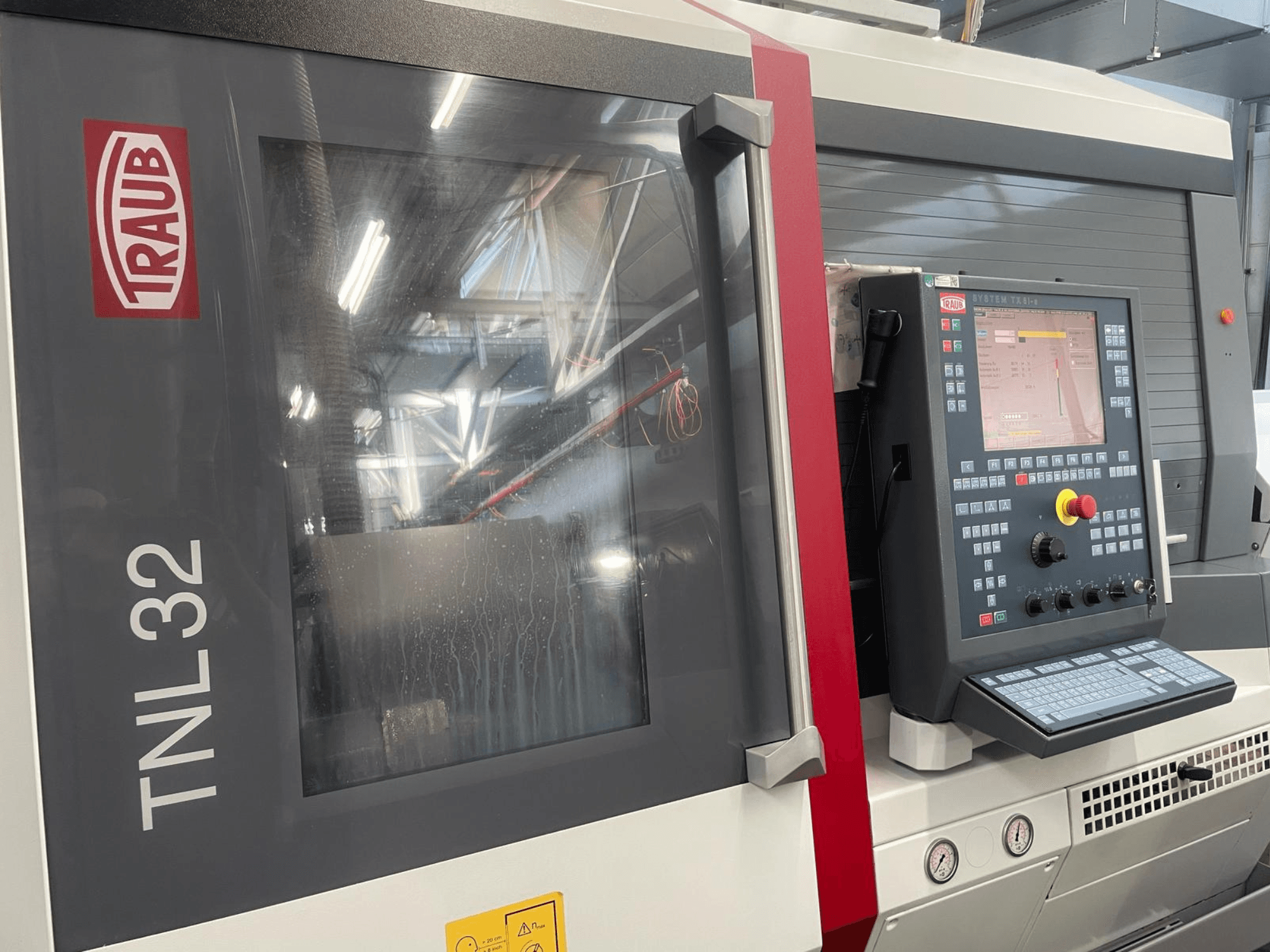 Vorderansicht der Traub TNL32 CNC-Drehmaschine mit Bedienfeld mit Tasten, Bildschirm und schlankem Metallgehäuse.
