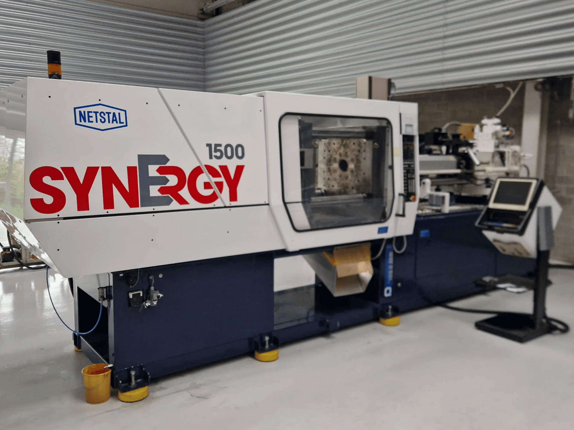 Hydraulische Spritzgiessmaschine Netstal Synergy 1500-460, Frontansicht mit Bedienfeld und offenem Spritzbereich.