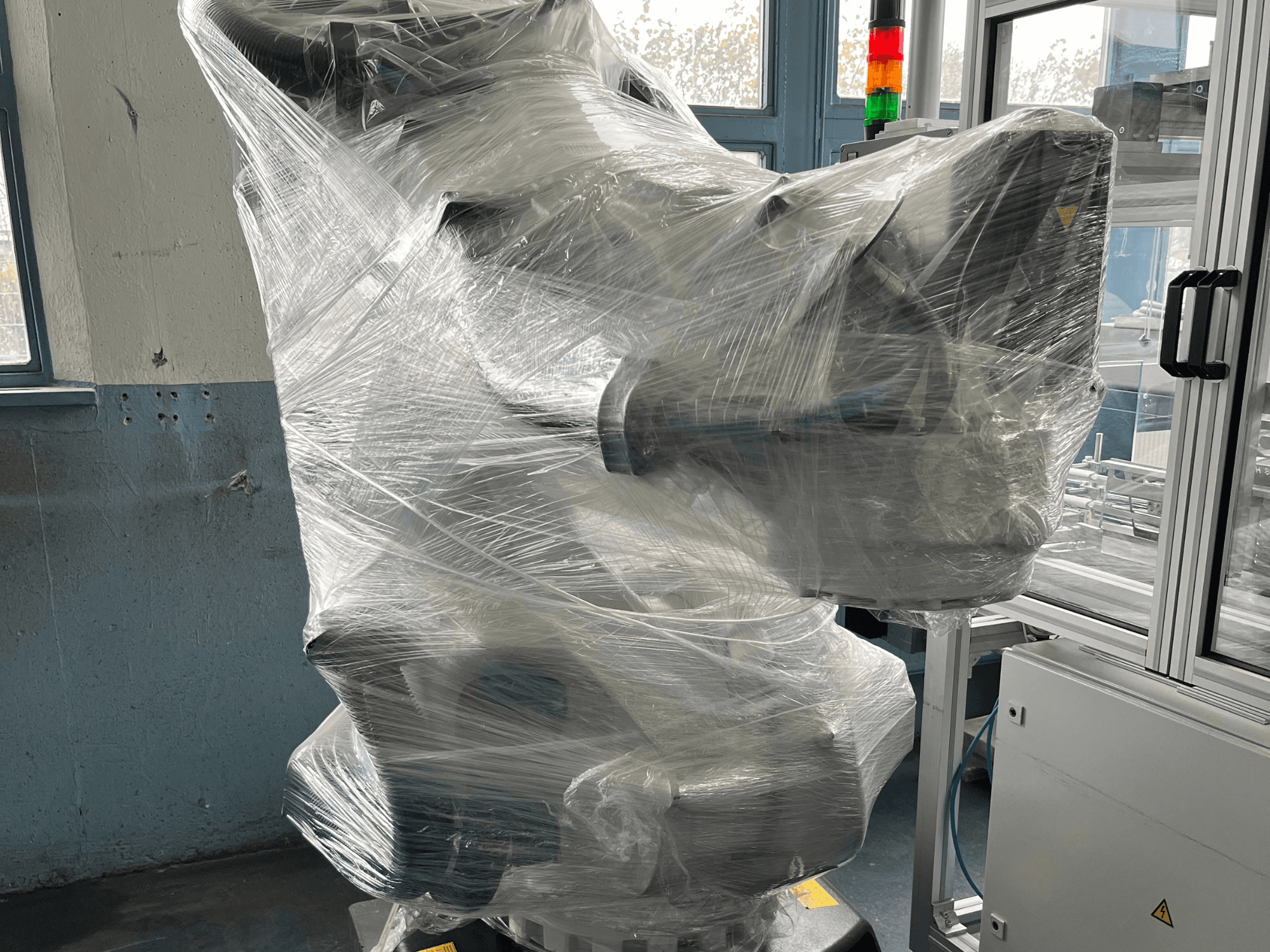 Industrie-Roboterarm in Kunststoff verpackt, Vorderansicht. Einschließlich Steuereinheit und Kontrollleuchte. Marke nicht sichtbar.