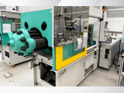 Spritzgießmaschine, hellblau und gelb, Vorderansicht, mit sichtbarem Werkzeug und Bedienfeld mit Etiketten.