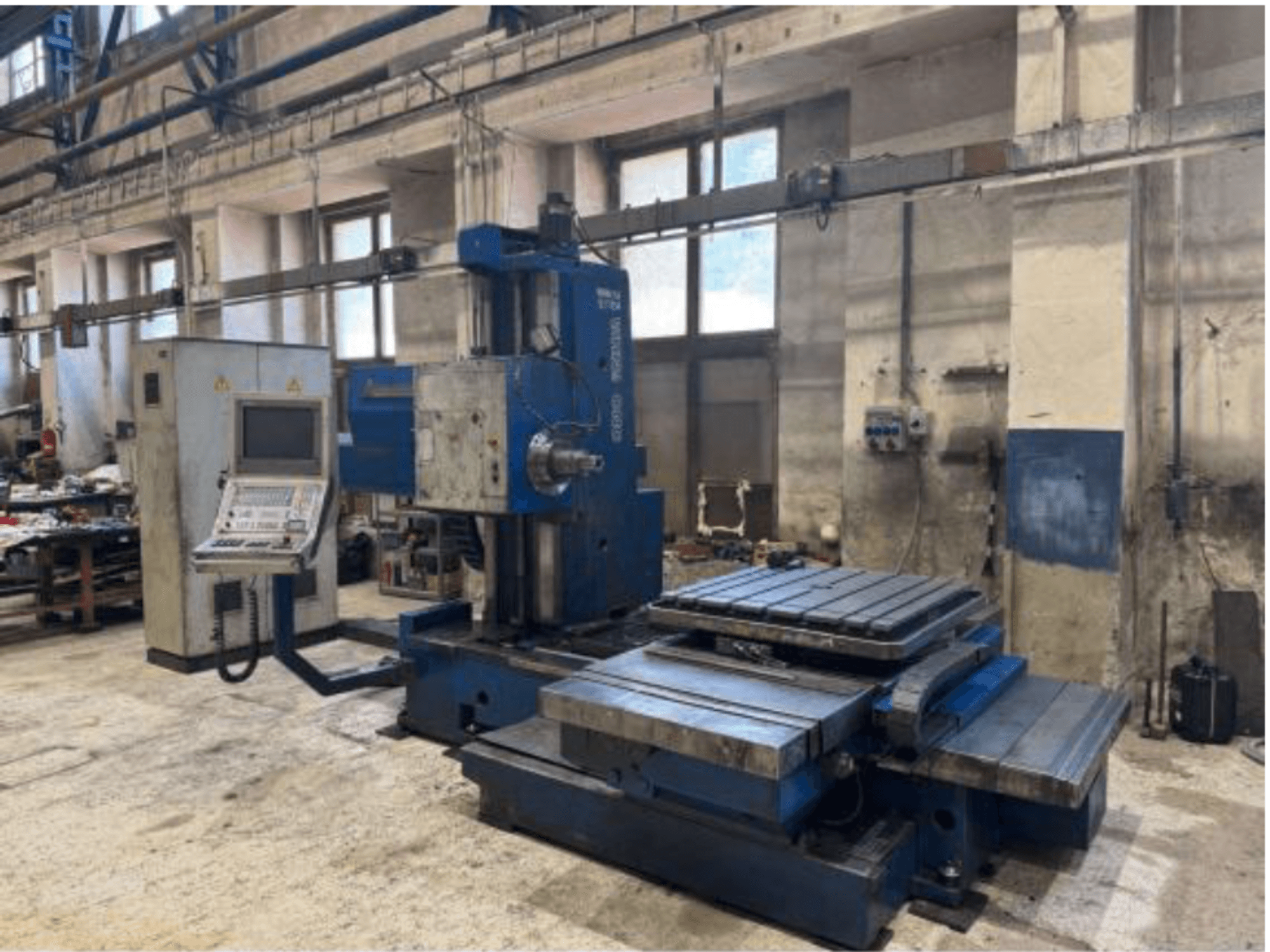 CNC-Bohrmaschine TOS WHN 9 B in Frontansicht, mit Bedienfeld und großem Arbeitstisch, in einer Werkstattumgebung.