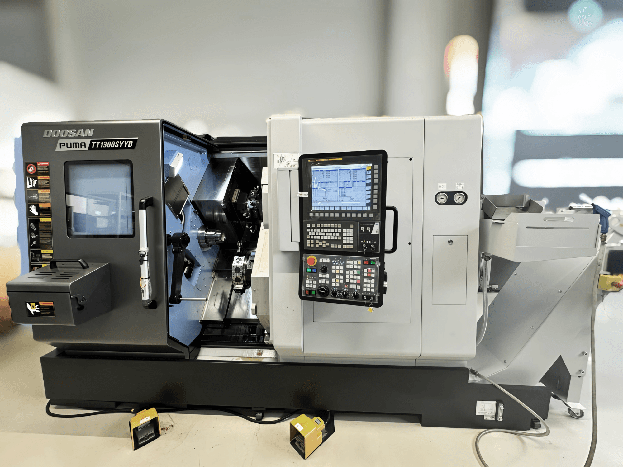 Doosan Puma TT1300SYYB Dreh-Fräszentrum in der Seitenansicht, mit Bedienfeld und Maschineninnenraum mit sichtbaren Werkzeugen.