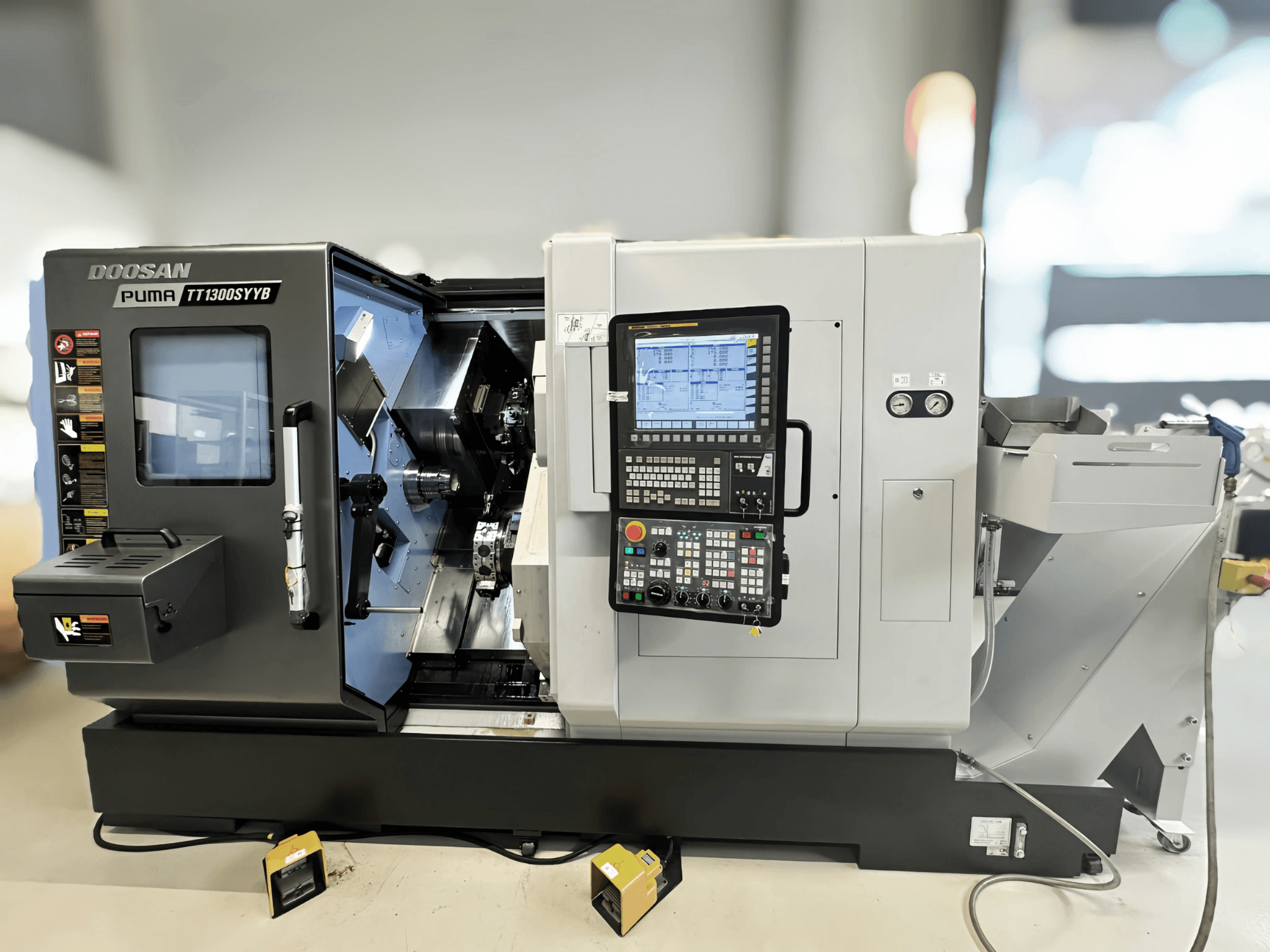 Doosan Puma TT1300SYYB Dreh-Fräszentrum in der Seitenansicht, mit Bedienfeld und Maschineninnenraum mit sichtbaren Werkzeugen.