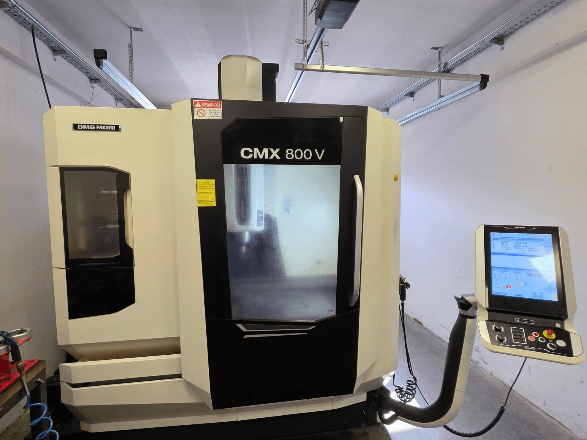 Vertikales Bearbeitungszentrum DMG MORI CMX 800V, Vorderansicht, mit Touchscreen-Bedienfeld und deutlicher Sicherheitsbeschilderung.