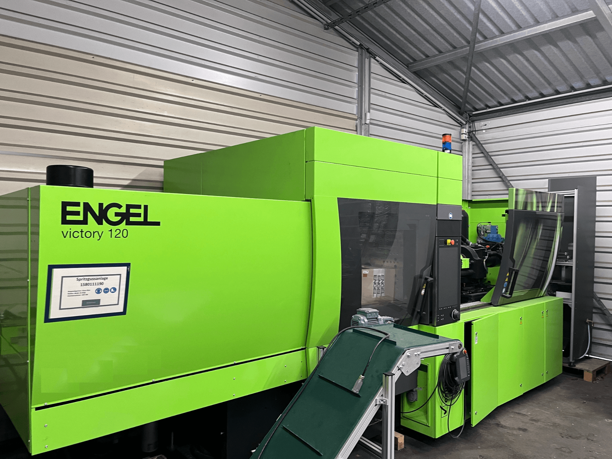Grüne hydraulische Spritzgießmaschine Engel Victory 120 BMG, Frontansicht mit Bedienfeld und Maschinenkomponenten.