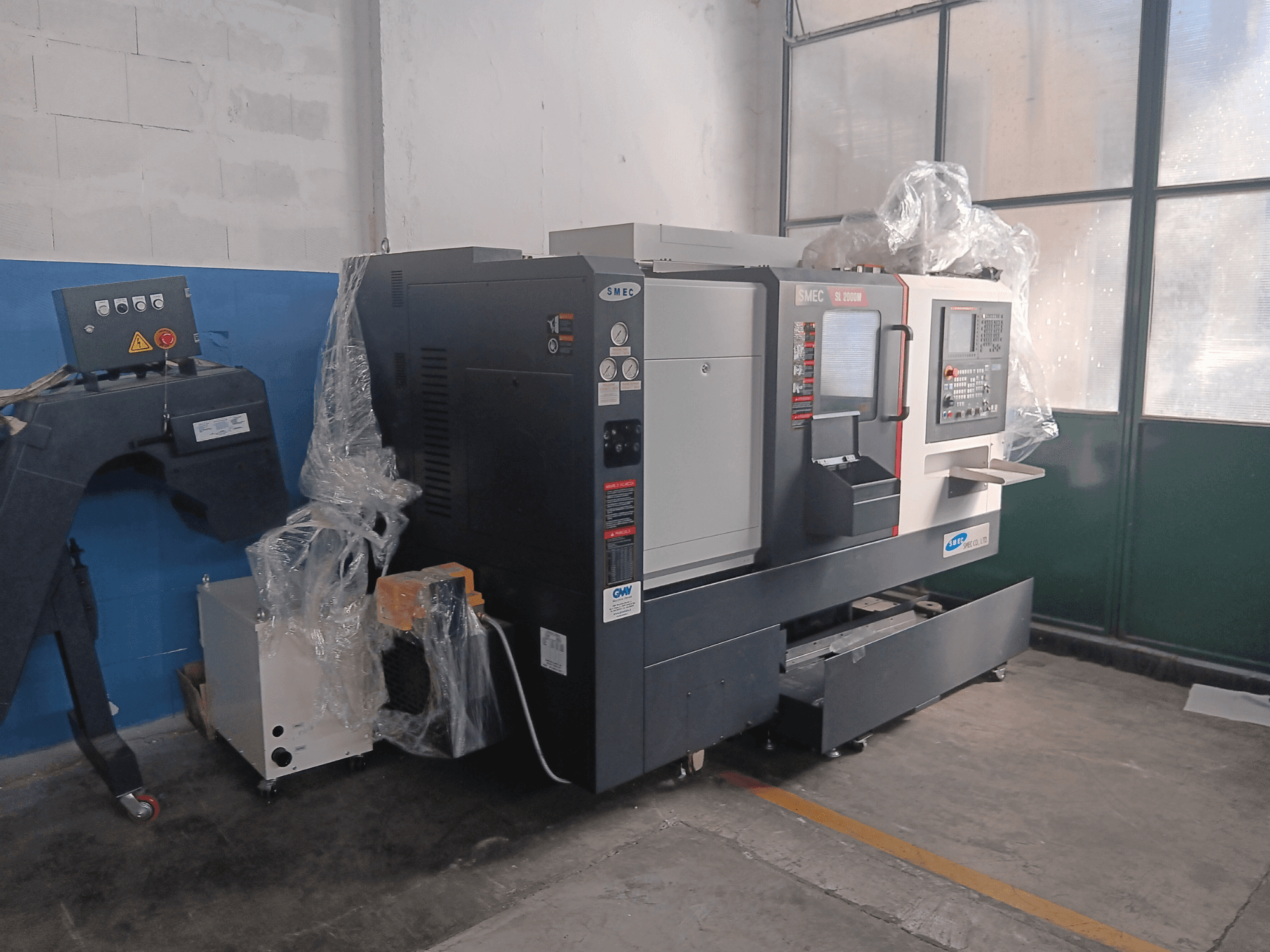 SMEC SL2000M B TYPE horizontale Drehmaschine, Seitenansicht, mit Bedienfeld und Schutzfolie.