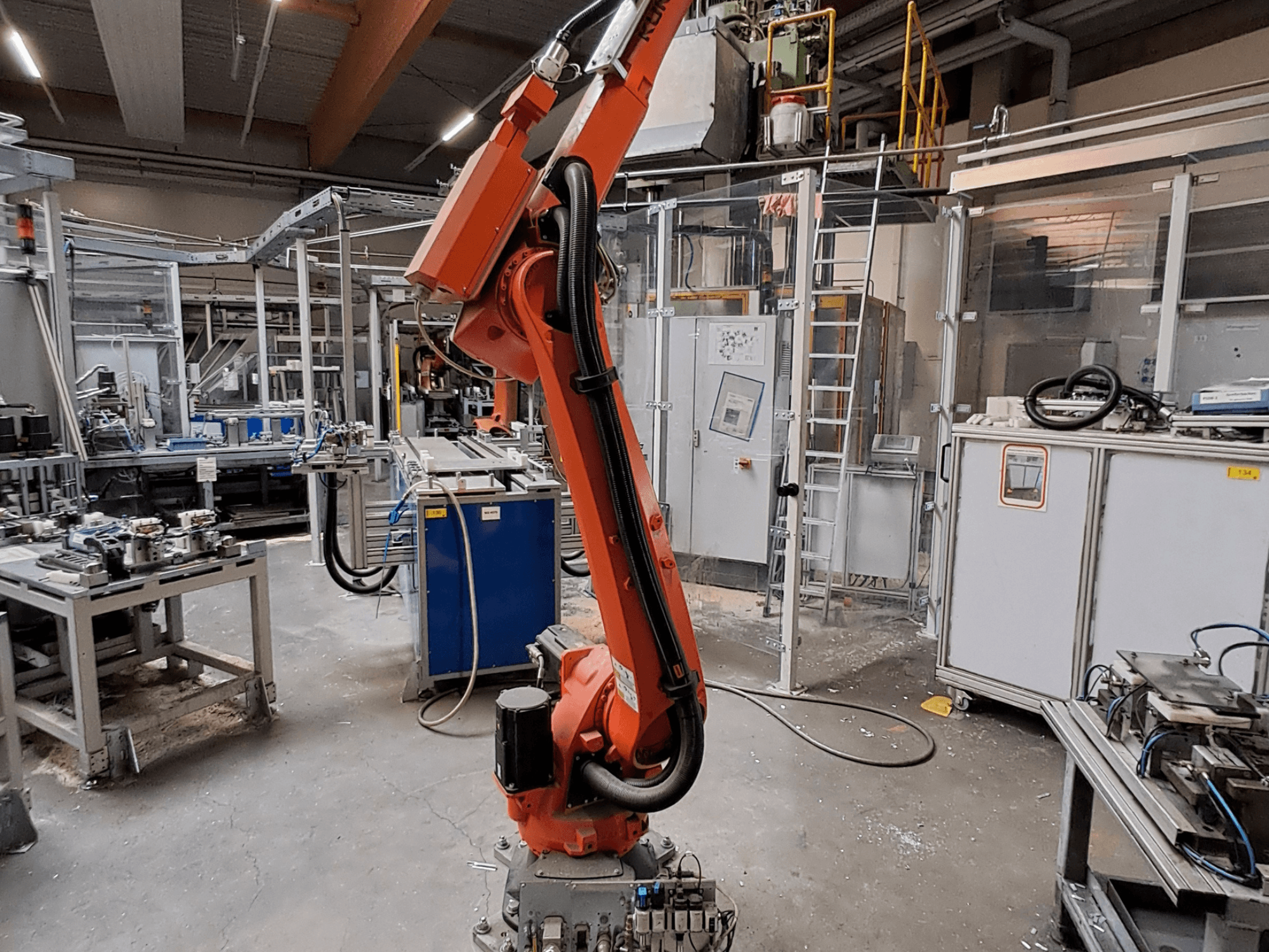 KUKA KR 26 R3100/SEL-Roboterarm in einer industriellen Umgebung, dargestellt in Seitenansicht mit Betriebsausstattung im Hintergrund.