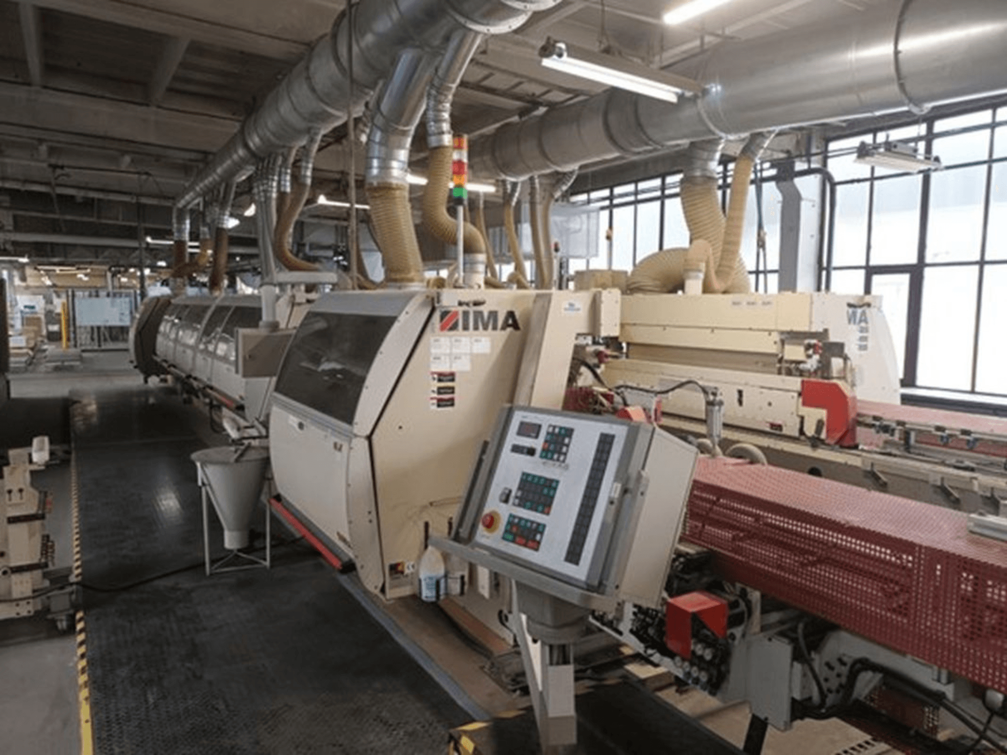 IMA-Industriemaschinen in einer Fabrikumgebung, Vorderansicht, mit Schalttafeln und Absaugrohren.