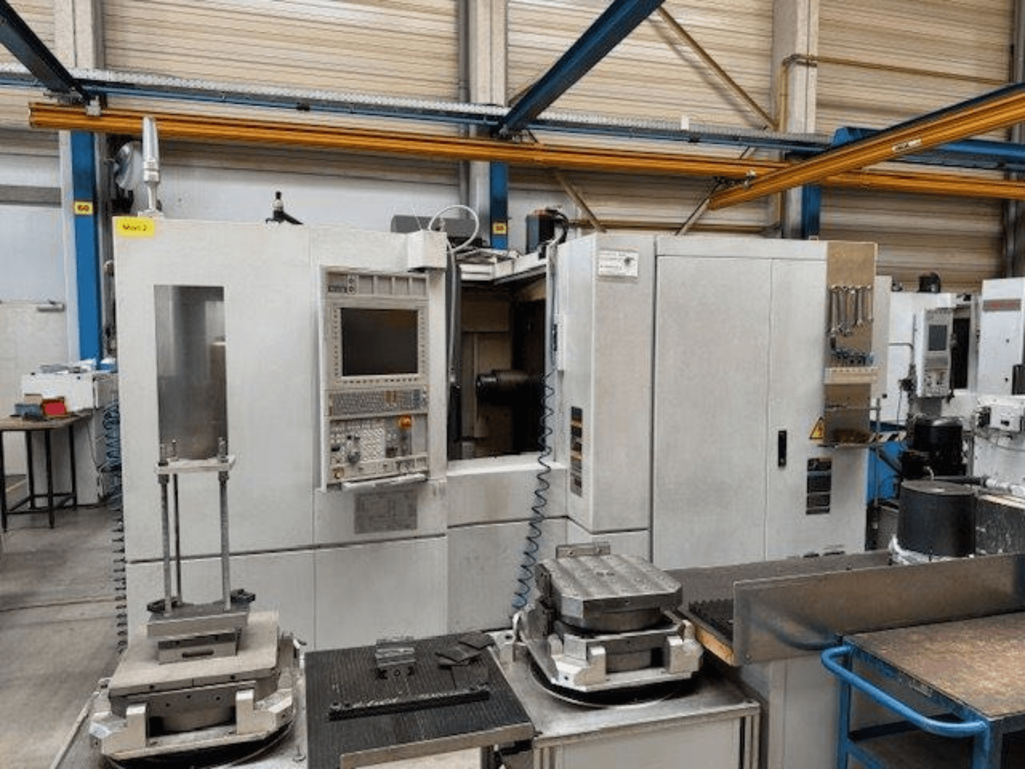 MORI SEIKI NH4000 DCG Frontansicht eines horizontalen Bearbeitungszentrums mit Bedienfeld und Werkstücken auf dem Tisch.