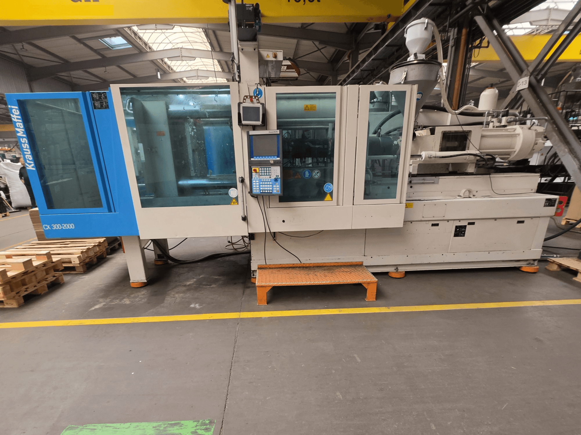 Krauss Maffei 300-2000 CX hydraulische Spritzgießmaschine, Seitenansicht mit Bedienfeld und großen Fenstern.