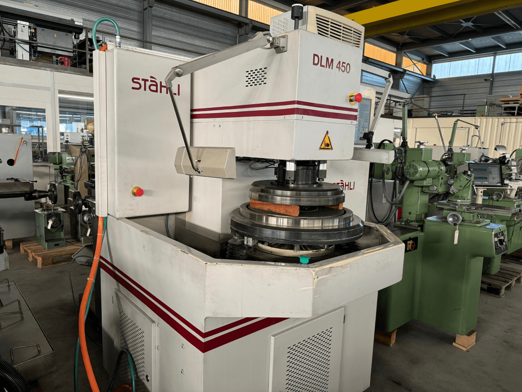 Flachschleifmaschine STAEHLI DLM 450, Vorderansicht mit Schleifscheibe und Bedienfeld, in einer industriellen Umgebung.