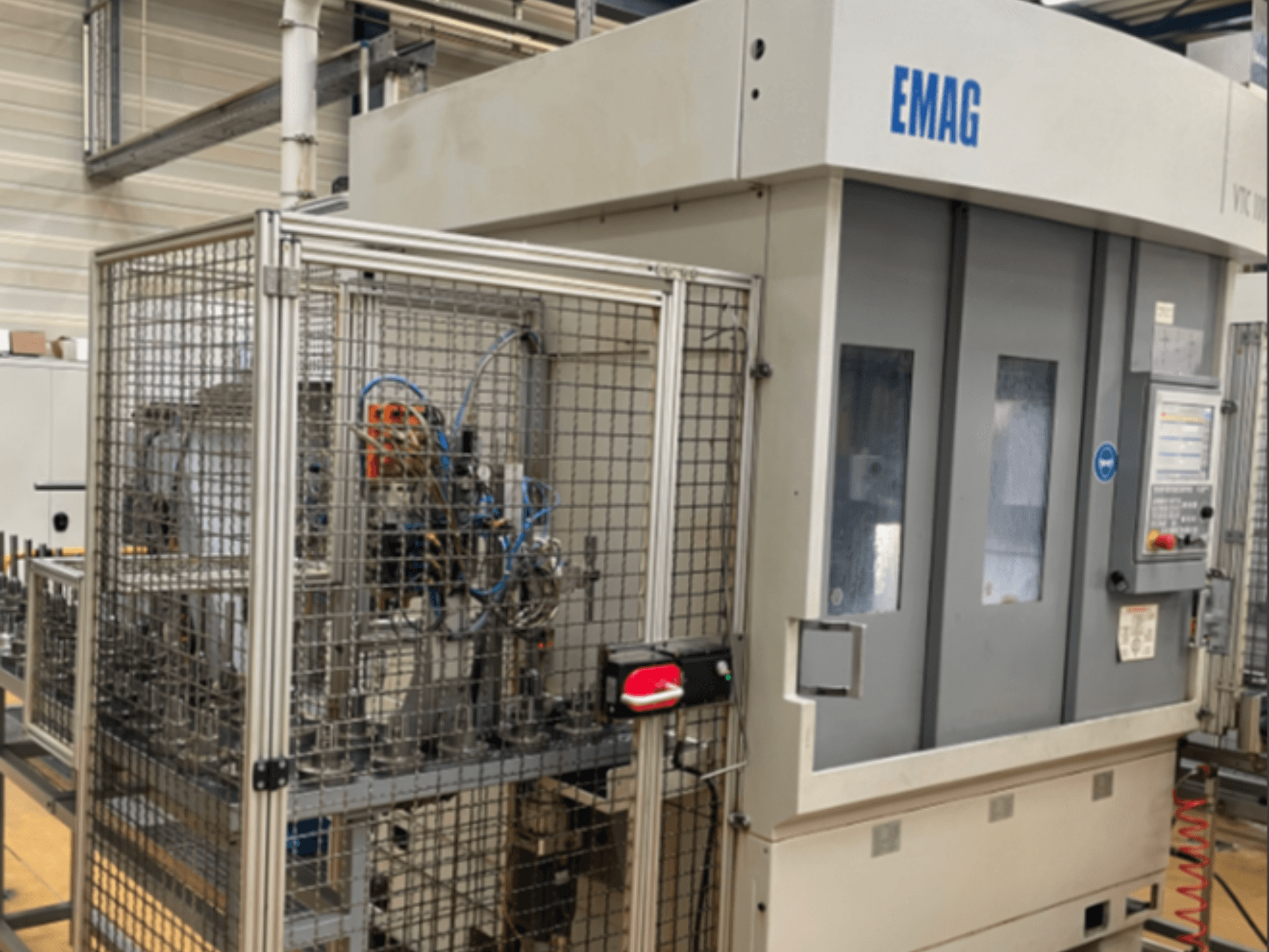 EMAG VTC 100 Vertikaldrehmaschine in Seitenansicht, mit Details zum Bedienfeld und zur Sicherheitsumzäunung.