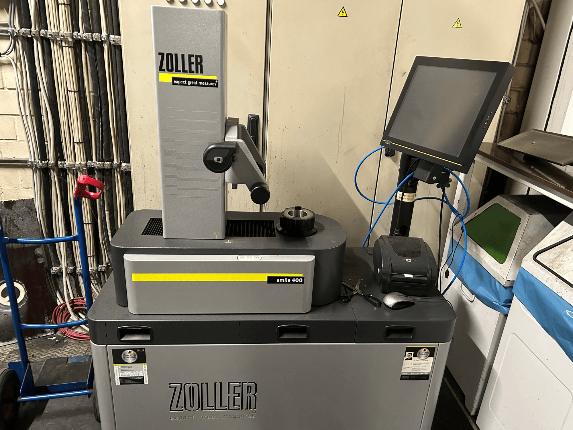 ZOLLER smile 400 Messgerät in grau, Frontansicht, mit Touchscreen, Werkzeughalter und Drucker auf einer Arbeitsfläche.