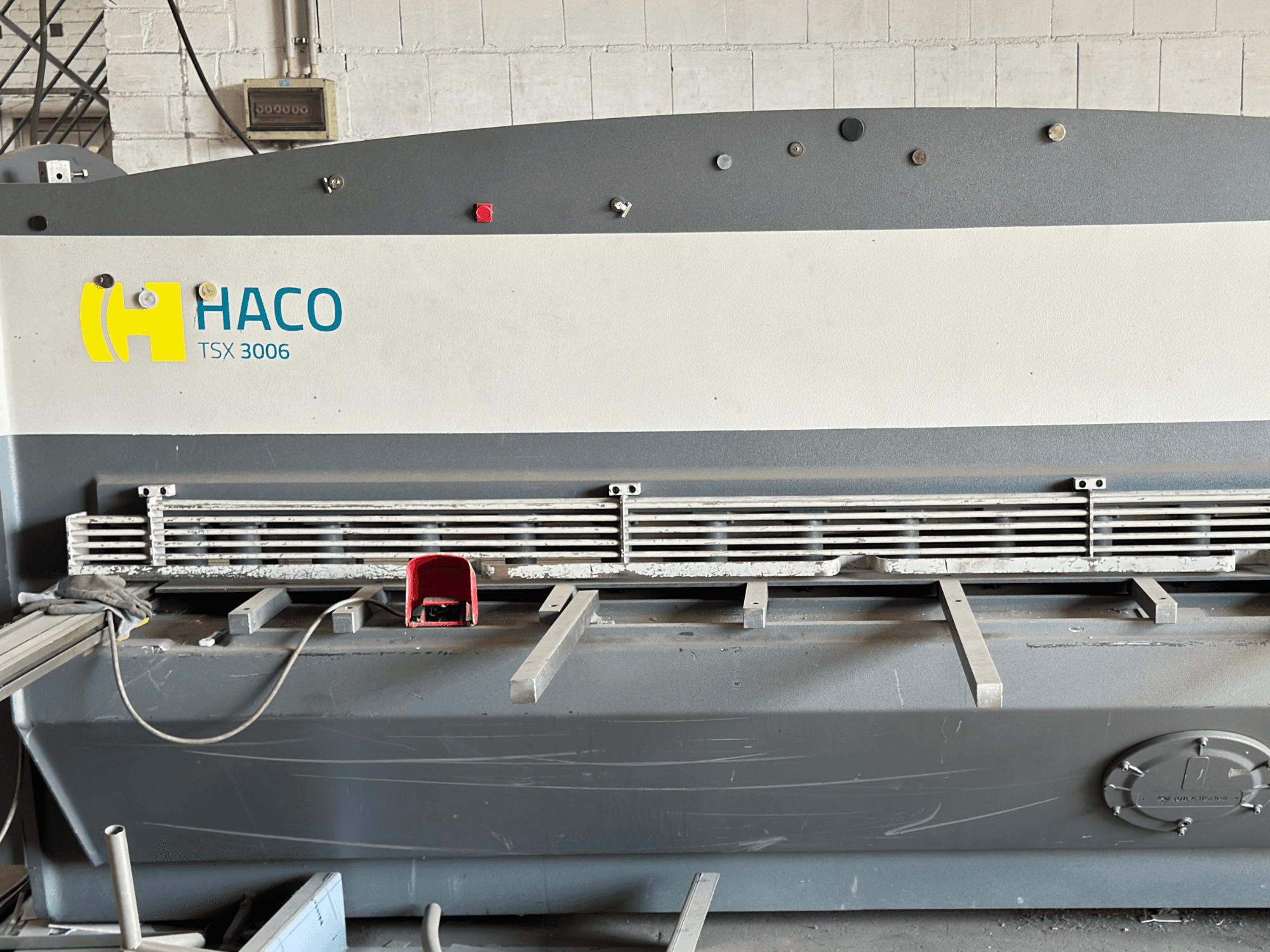 Hydraulische Schermaschine HACO TSX3006 MOT, Vorderansicht, mit Metallschneidemessern und Bedienpult, mit Angaben zur Bedienung.