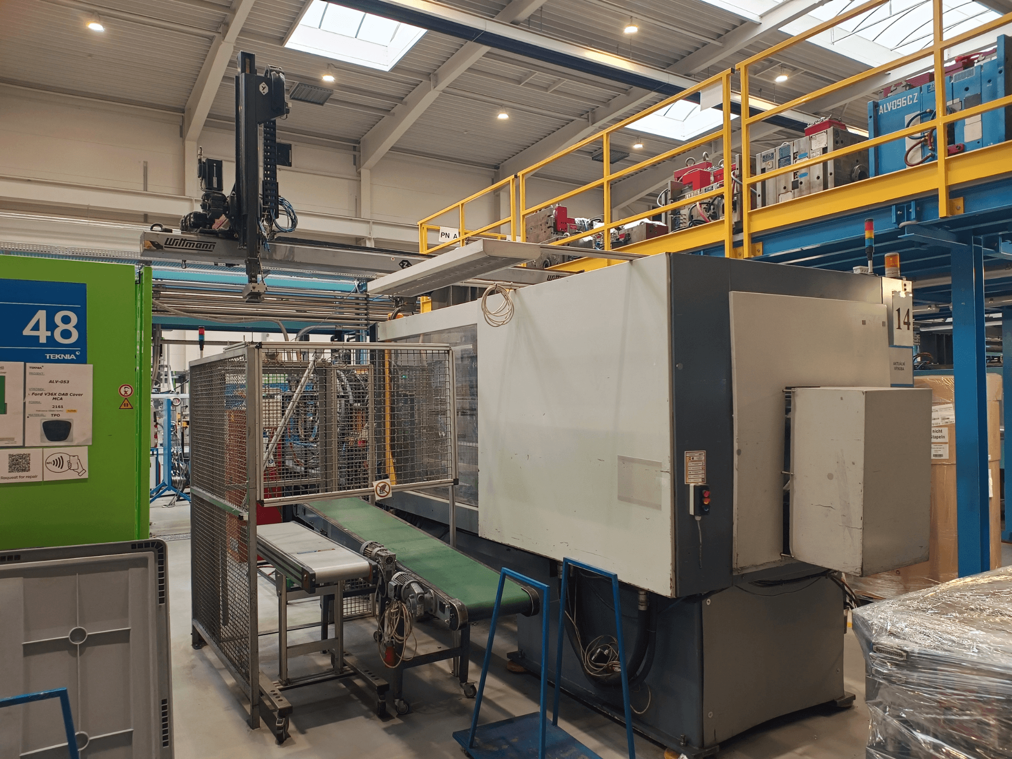 Industrielle Automatisierungsmaschine von Winmon, Seitenansicht mit Förderband, Bedienfeld und Sicherheitskäfig in einer Fabrikumgebung.