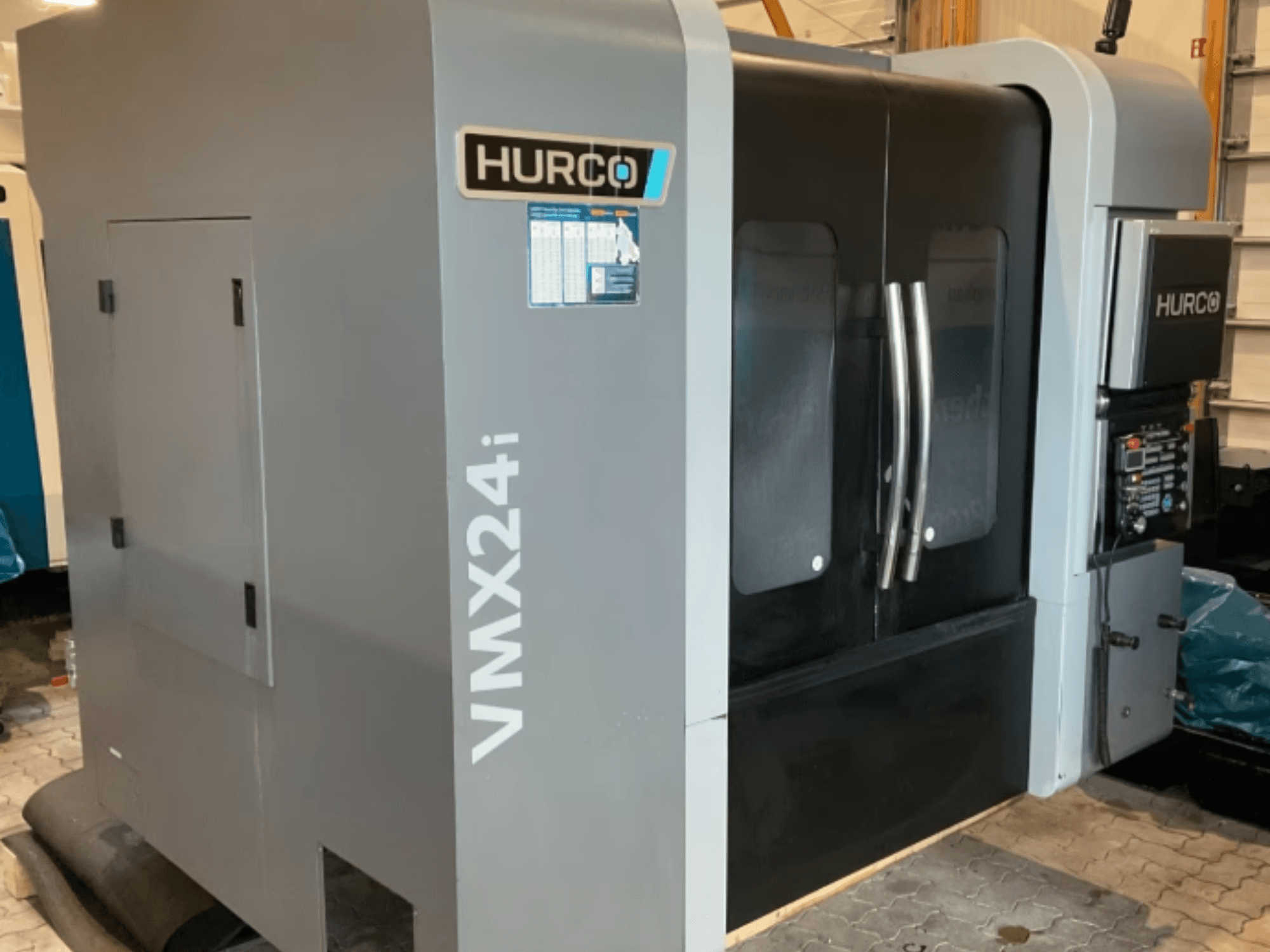 Vertikales Bearbeitungszentrum Hurco VMX 24i, Vorderansicht mit metallgrauem Gehäuse, schwarzen Verkleidungen und Bedienoberfläche.