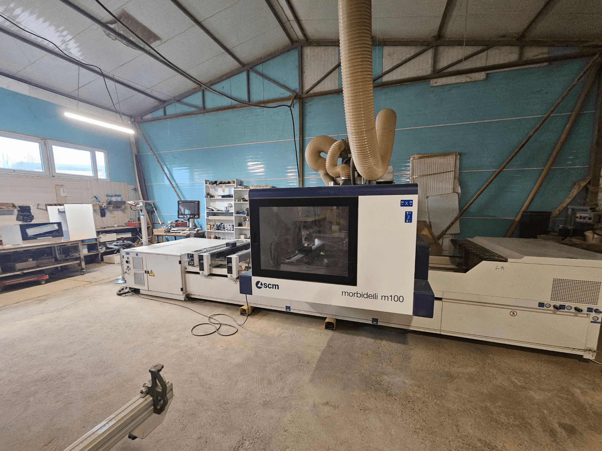 SCM Morbidelli M100 CNC-Maschine in einer Werkstatt, Vorderansicht, mit Staubabsaugung und Bedienfeld.