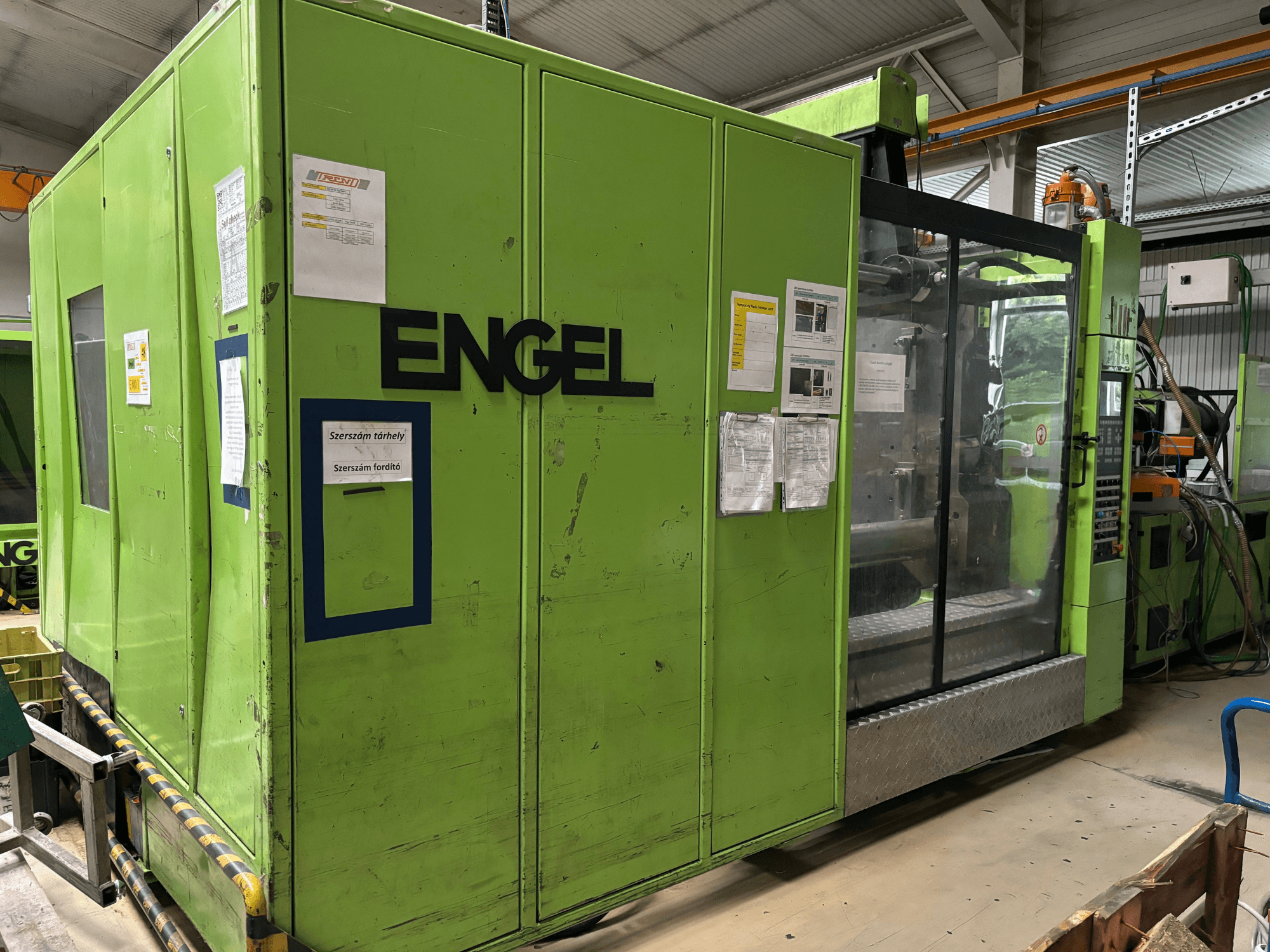 Hydraulische Spritzgießmaschine Engel DUO 5550/800, Frontansicht, mit grünem Gehäuse und transparenter Zugangsverkleidung.