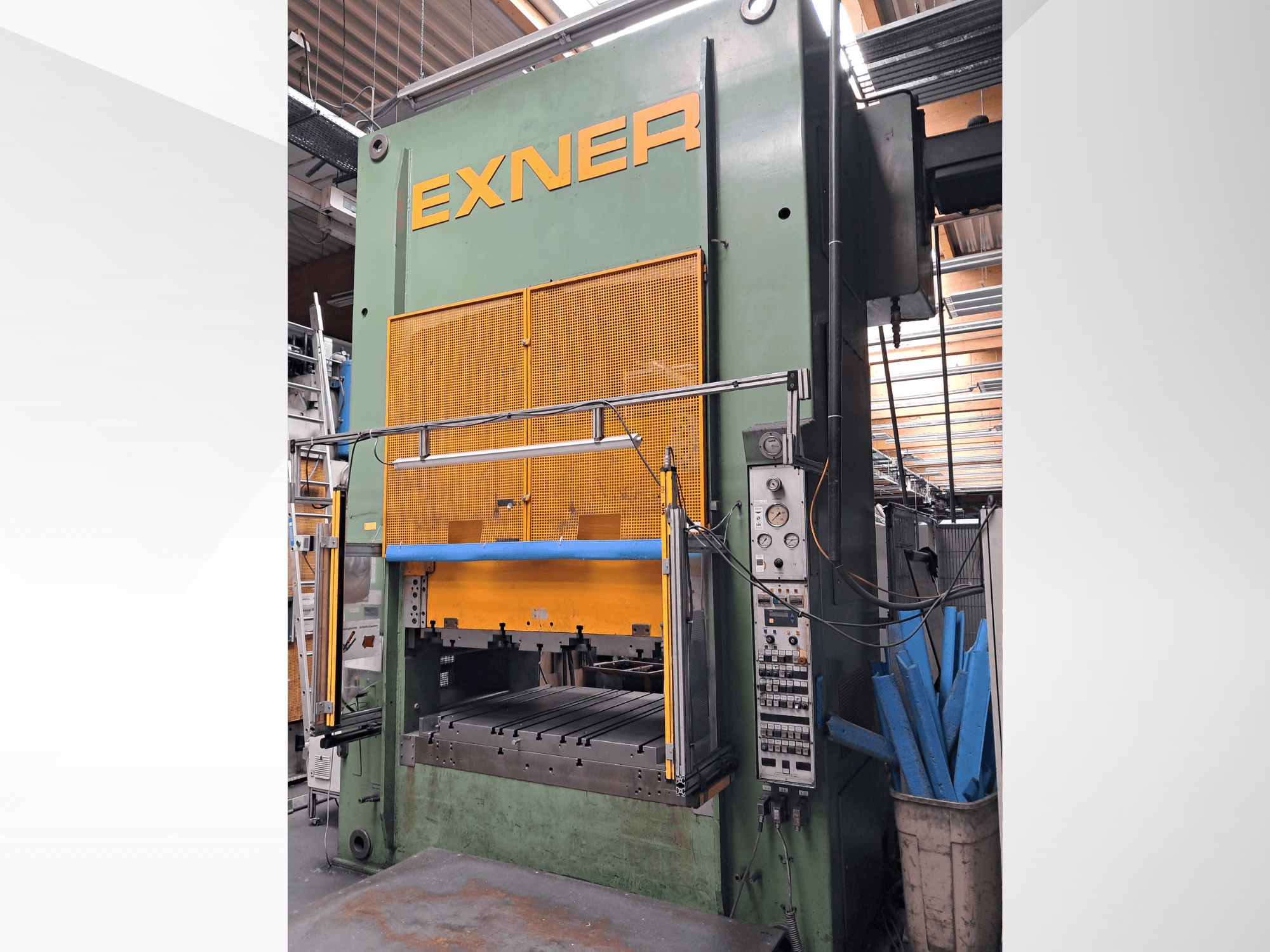 Hydraulikpresse EXNER EX SBR 150, Vorderansicht; mit Bedienelementen, blauer Sicherheitsstange und Schutzgitter, in einer Werkstattumgebung.