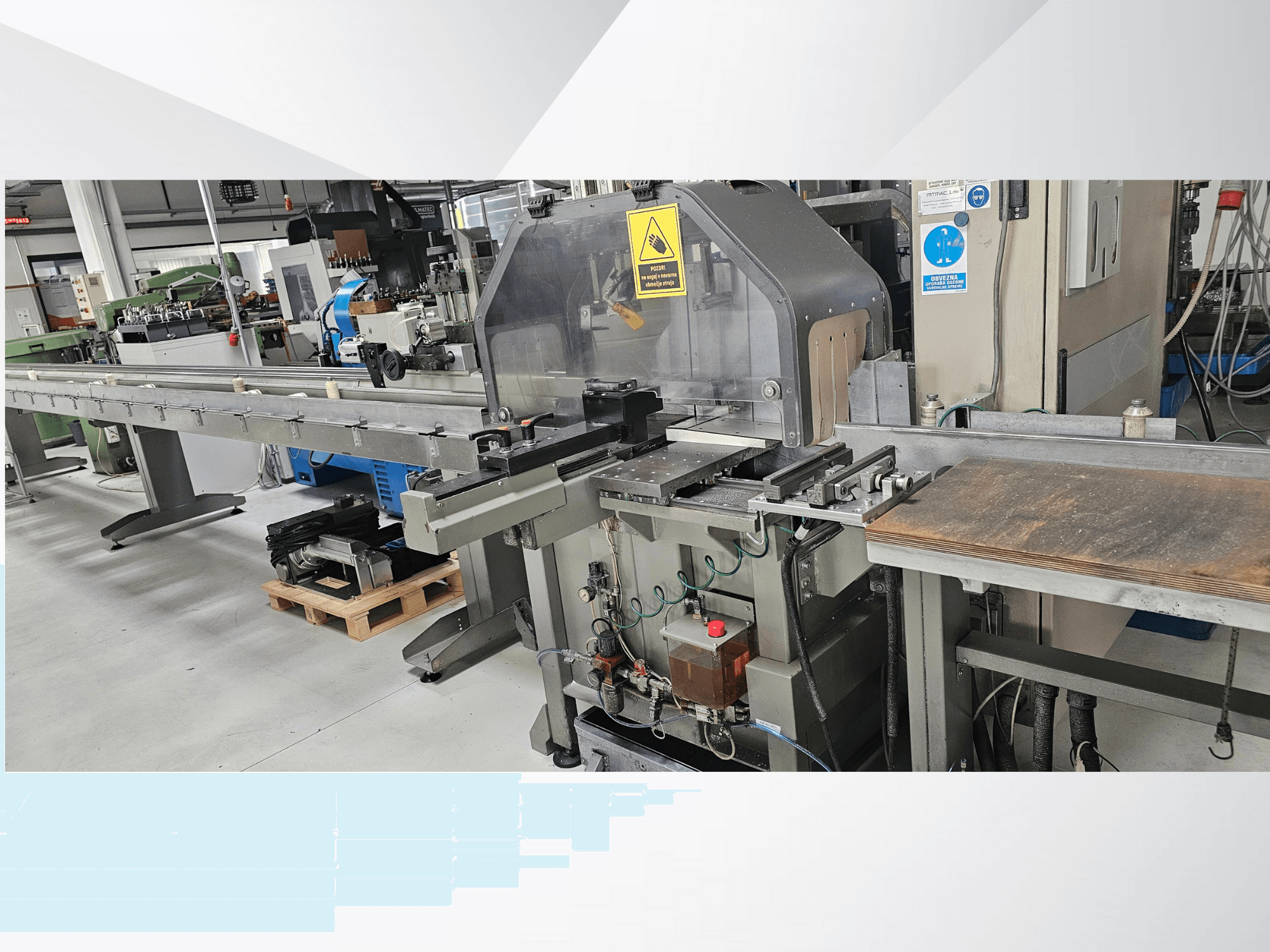 Industrielle Schneidemaschine aus der Seitenansicht, mit langem Förderband, Bedienfeld und Sicherheitshinweisen.