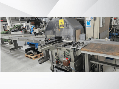 Industrielle Schneidemaschine aus der Seitenansicht, mit langem Förderband, Bedienfeld und Sicherheitshinweisen.