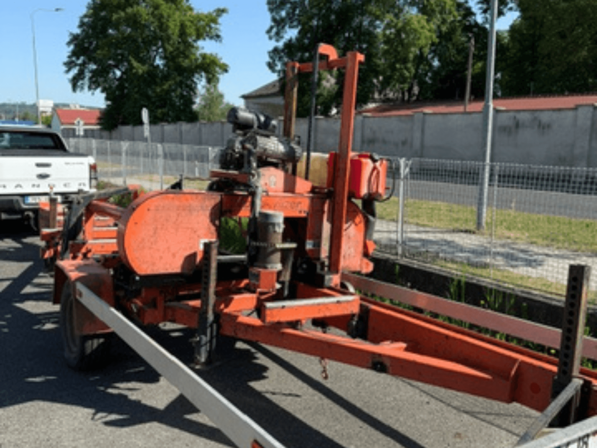 WOOD-MIZER LT40 Holzbandsäge in Orange, Seitenansicht auf einem Anhänger mit sichtbaren Rädern und Motorkomponenten.