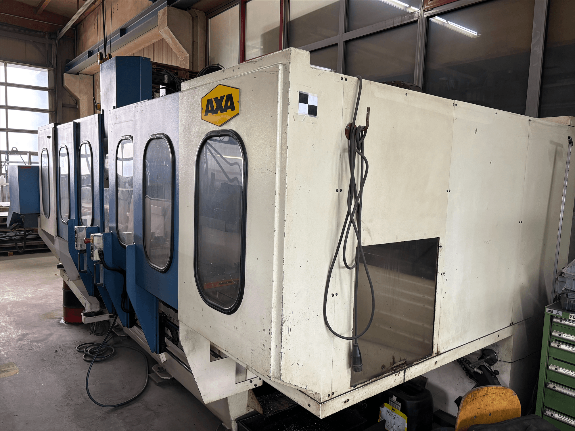 AXA VSC-1-M/C Vertikal-Bearbeitungszentrum, Vorderansicht, mit großem weißen Gehäuse und blauem Bedienfeld.