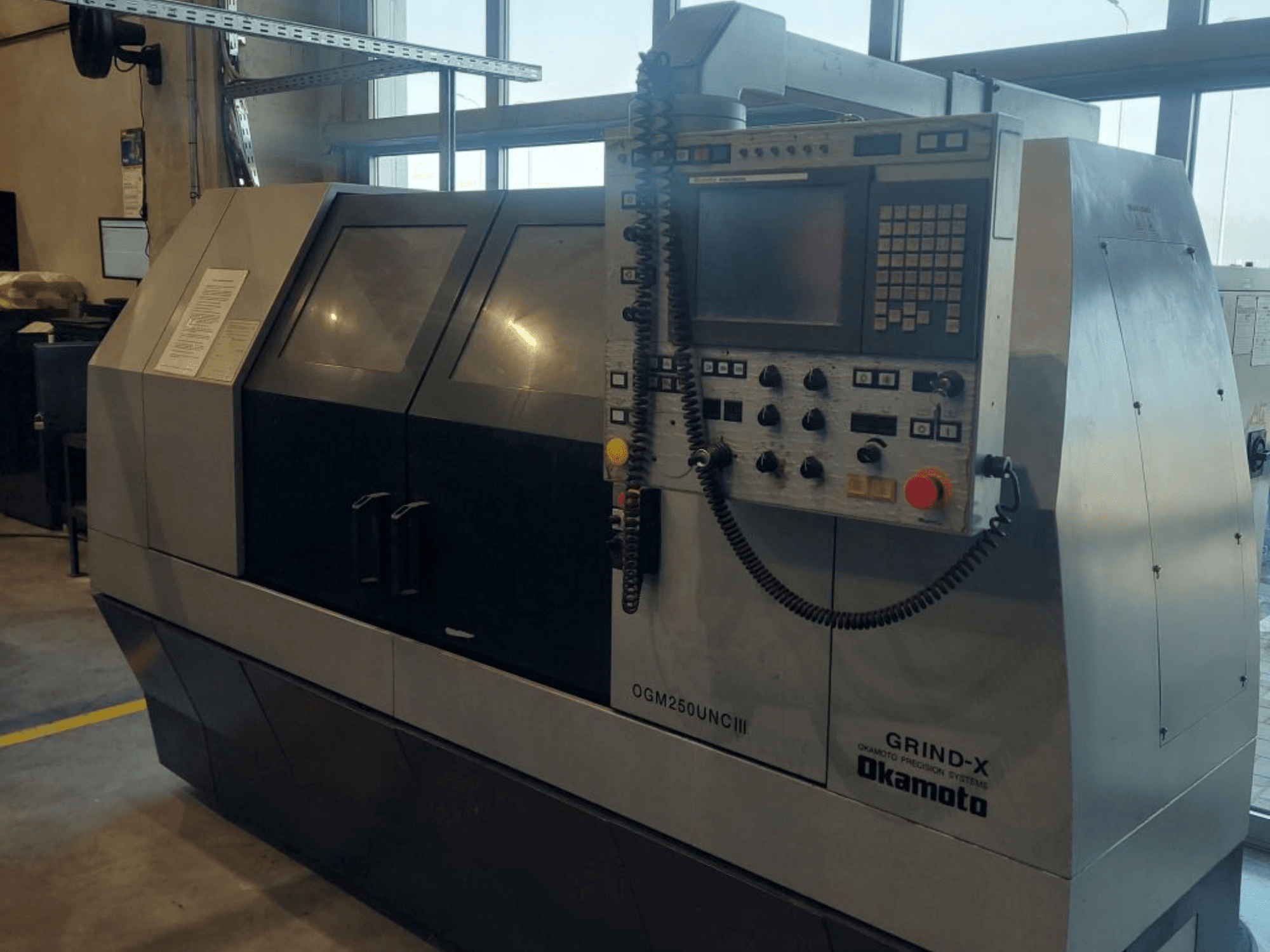 Zylinderschleifmaschine OKAMOTO OGM 250 UNC III, Vorderansicht, mit Blick auf das Bedienfeld und das Design mit zwei Fenstern.