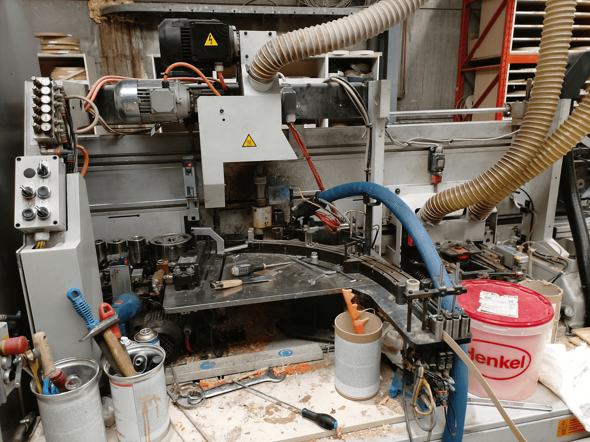 BIESSE Edge Stram B1 Kantenanleimmaschine in der Frontansicht mit Maschinen, Schläuchen und Arbeitswerkzeugen inmitten von Holzspänen.