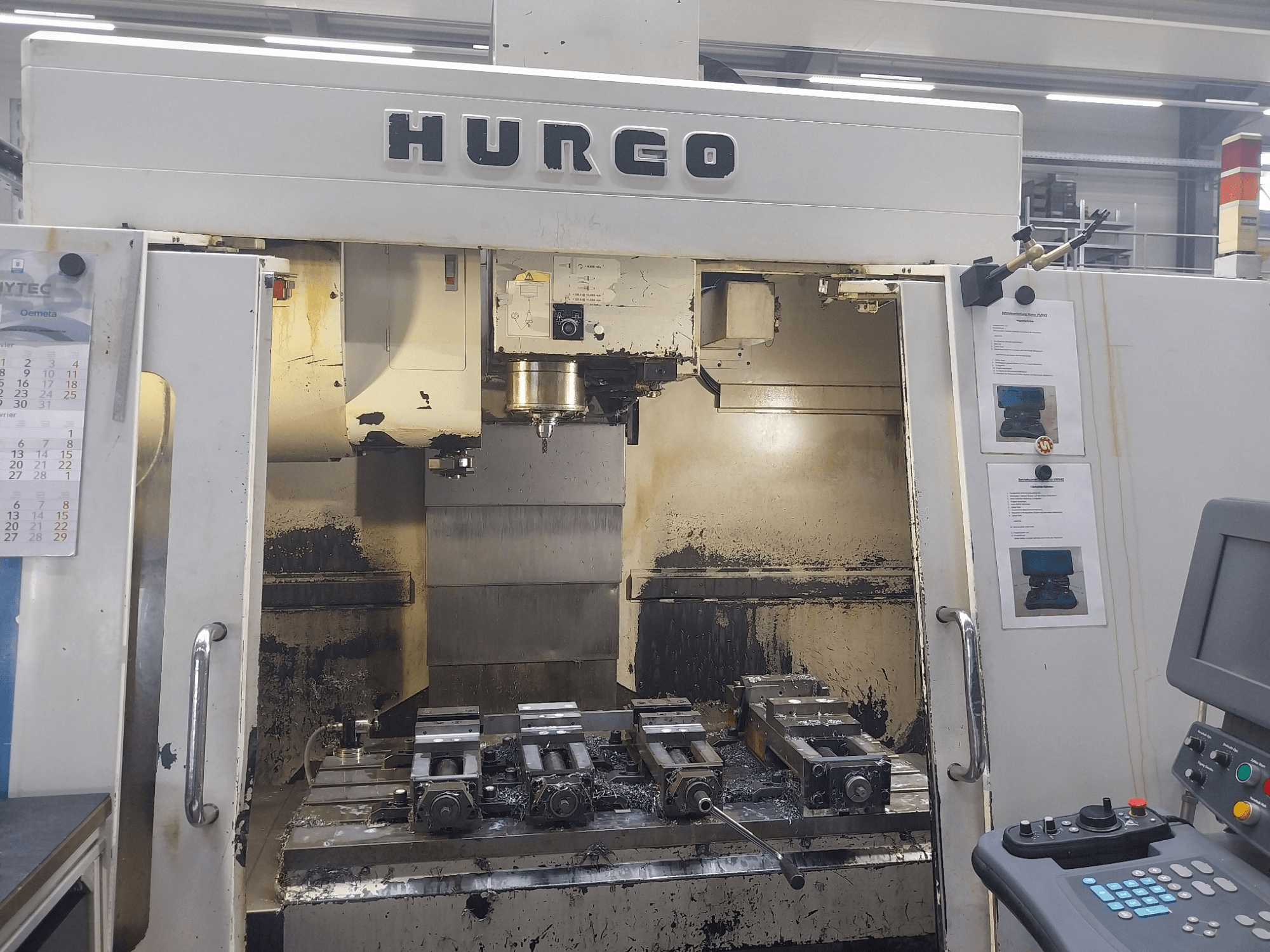 Hurco VMX 42 vertikales Bearbeitungszentrum, Vorderansicht, zeigt Arbeitstisch mit Vorrichtungen und Bedienfeld, leicht abgenutzter Zustand.