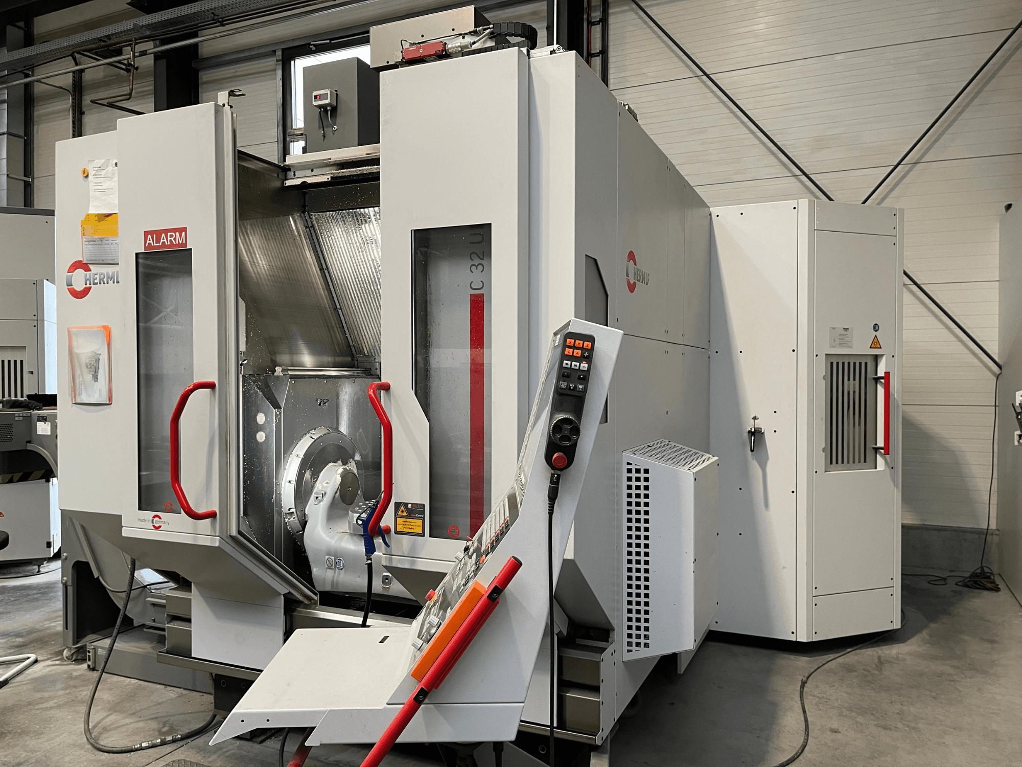 HERMLE C 32 U Universal-Bearbeitungszentrum in der Vorderansicht, mit Bedienfeld und roten Sicherheitsgriffen.