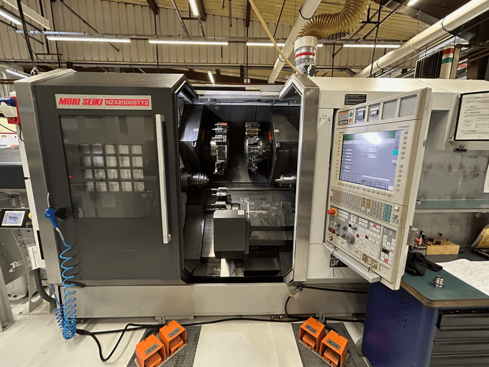 MORI SEIKI NZ2000 ST3Y3 Mehrspindel-Drehmaschine, Vorderansicht mit Bedienfeld und Bearbeitungsbereich.